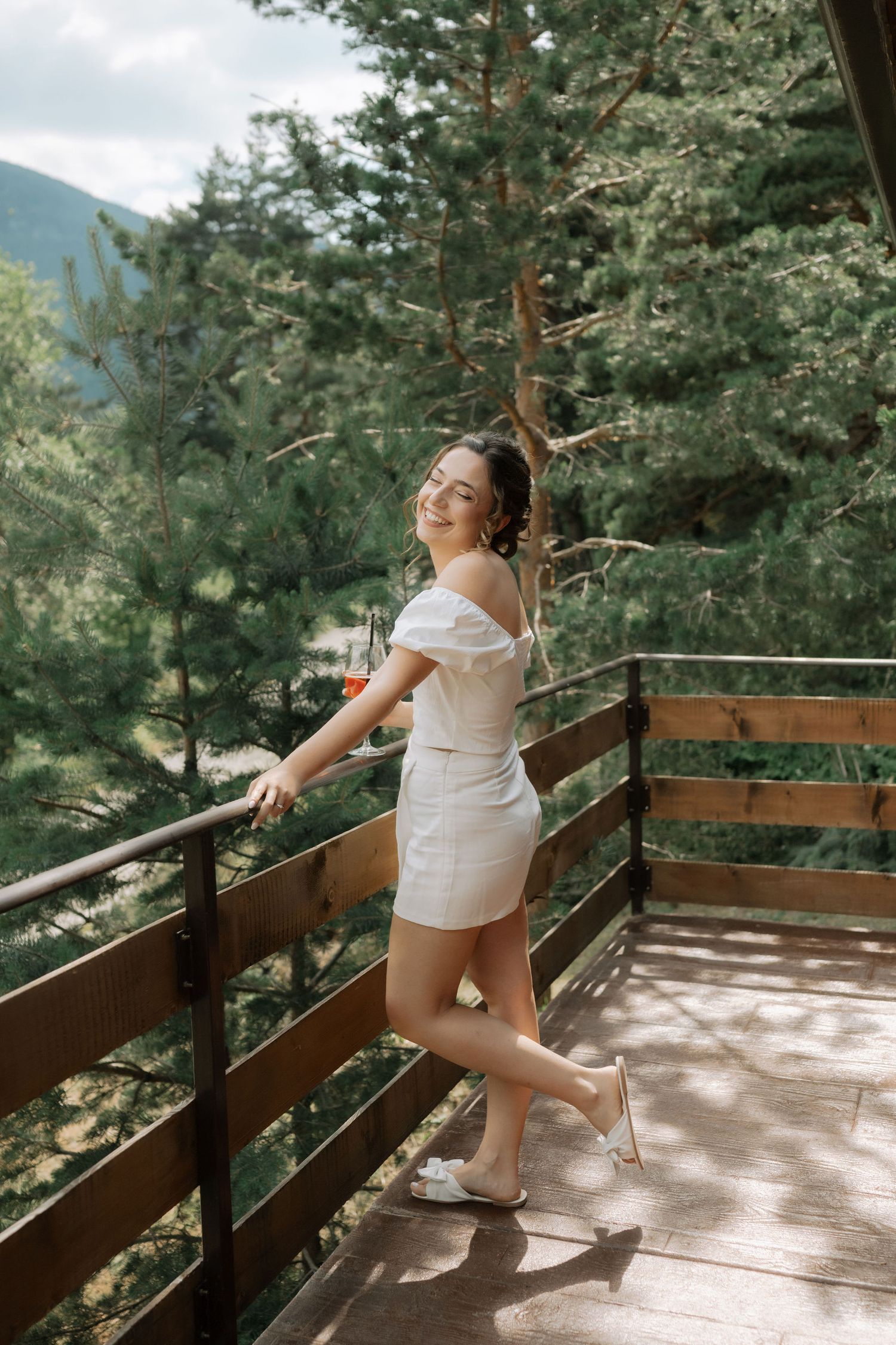 A series of photos showing someone in white clothing dancing on a sunny wooden deck surrounded by pine trees.