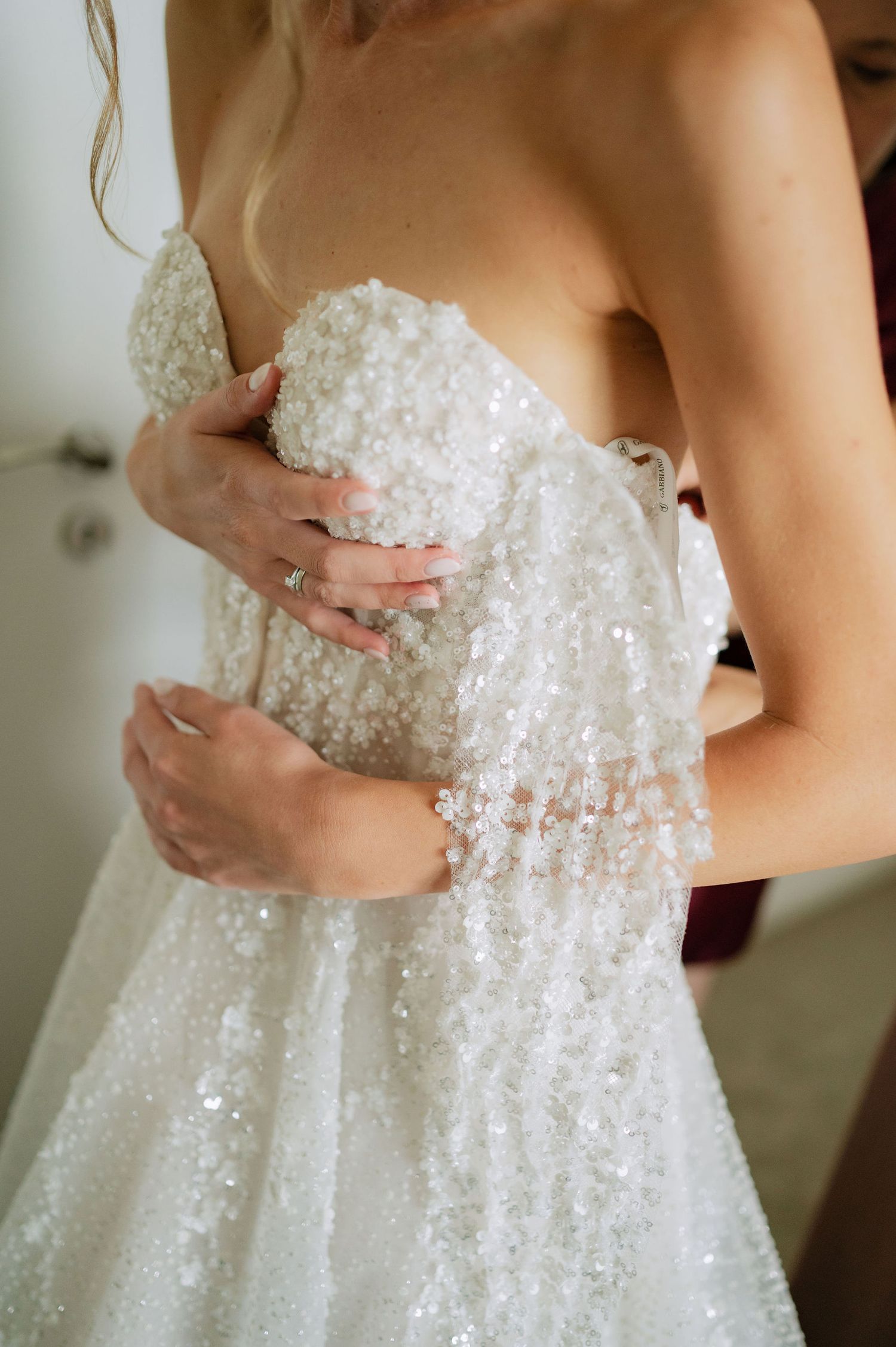 Close-up details of a sparkly white wedding dress with beaded embellishments.