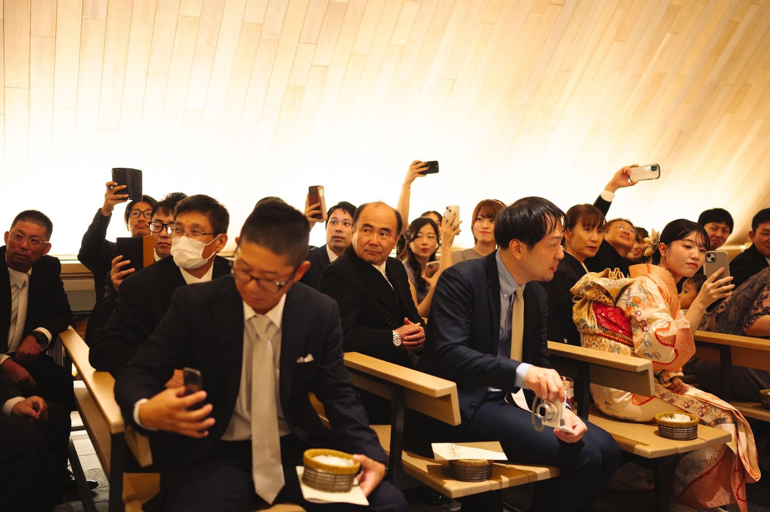 Crowd of formally dressed attendees seated in rows during an indoor celebration.