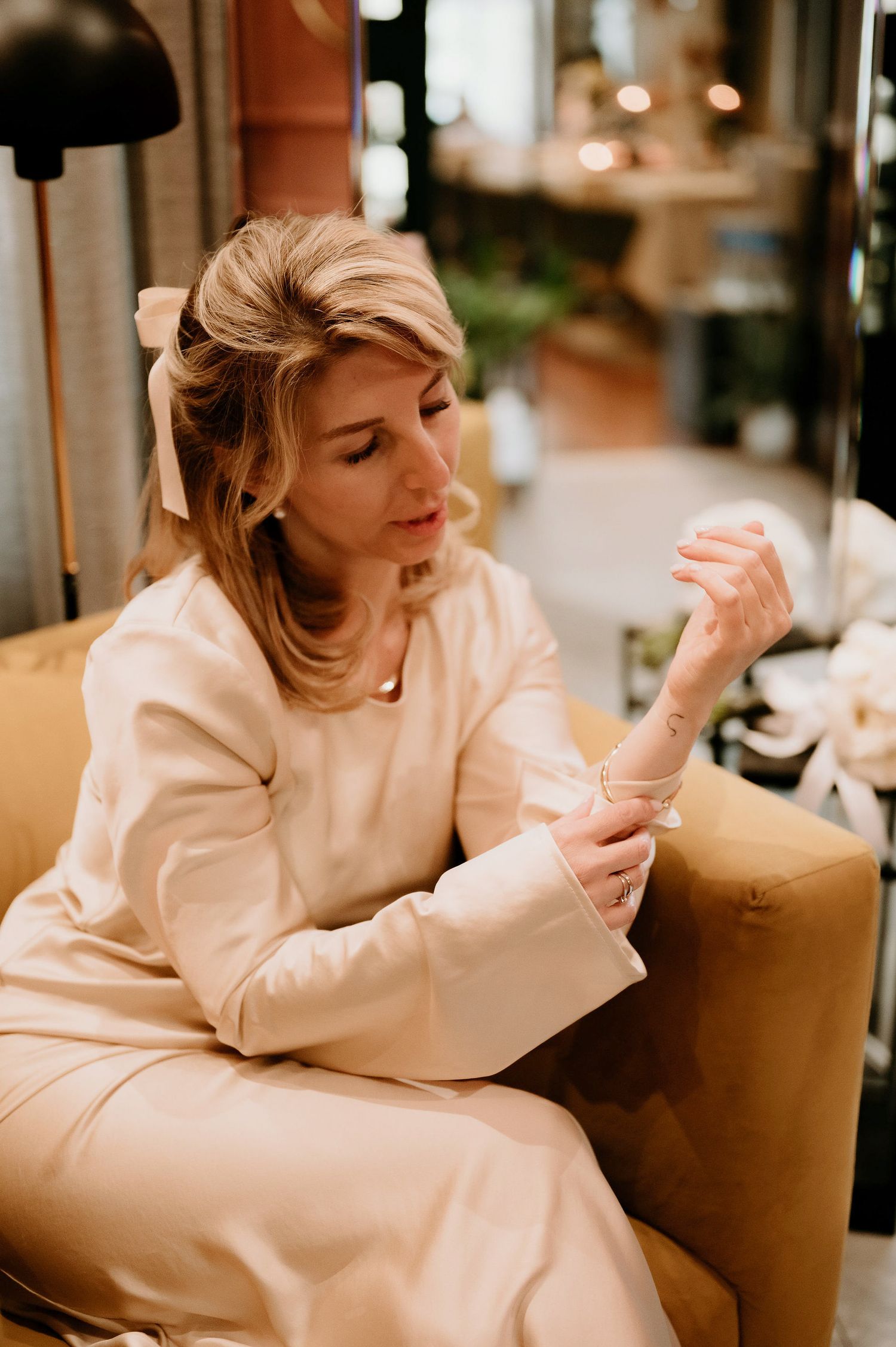 Person in white dress lounging thoughtfully on a brown couch.