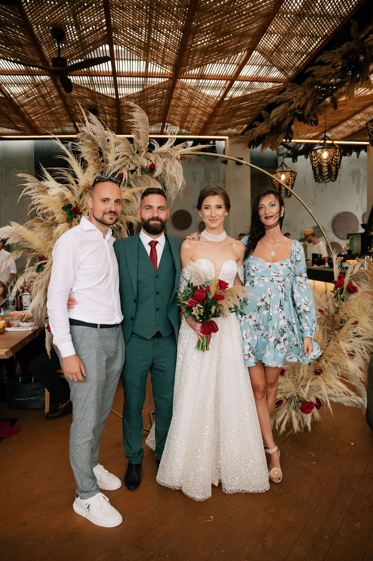 Small wedding group photo under wooden beamed ceiling with boho pampas grass decorations.