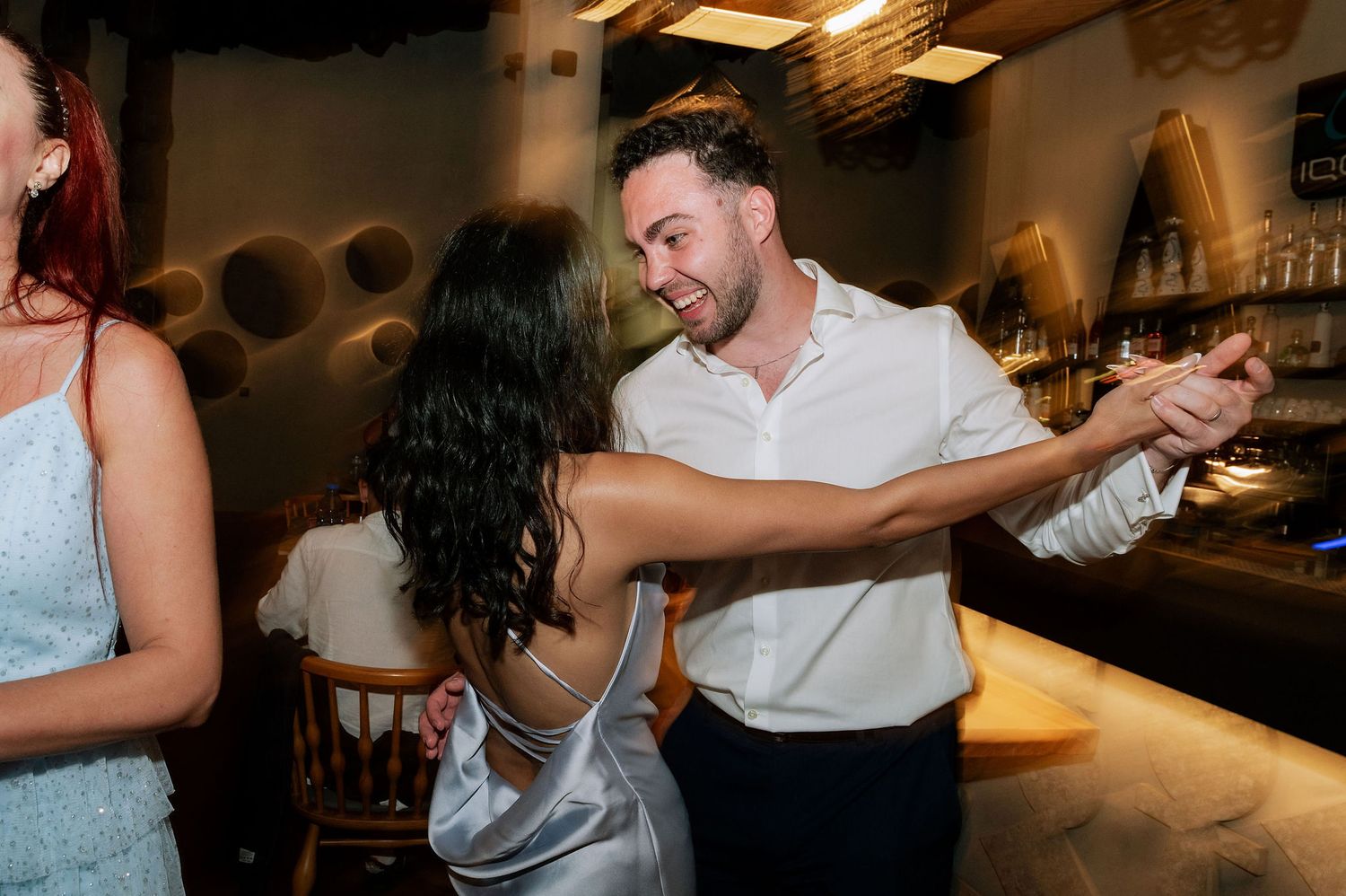Wedding celebration showing guests dancing together in a dimly lit venue.