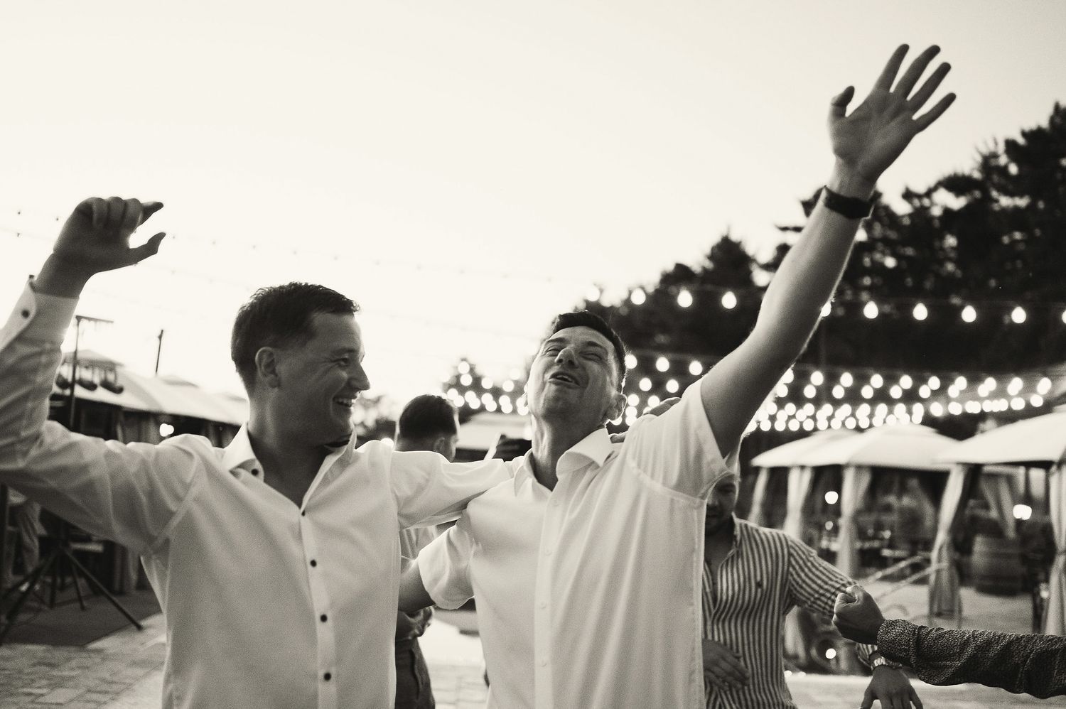 People raising their hands and dancing joyfully at an outdoor celebration.