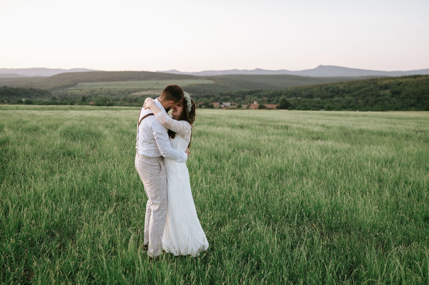 A couple shares an intimate moment in a vast field during golden hour.