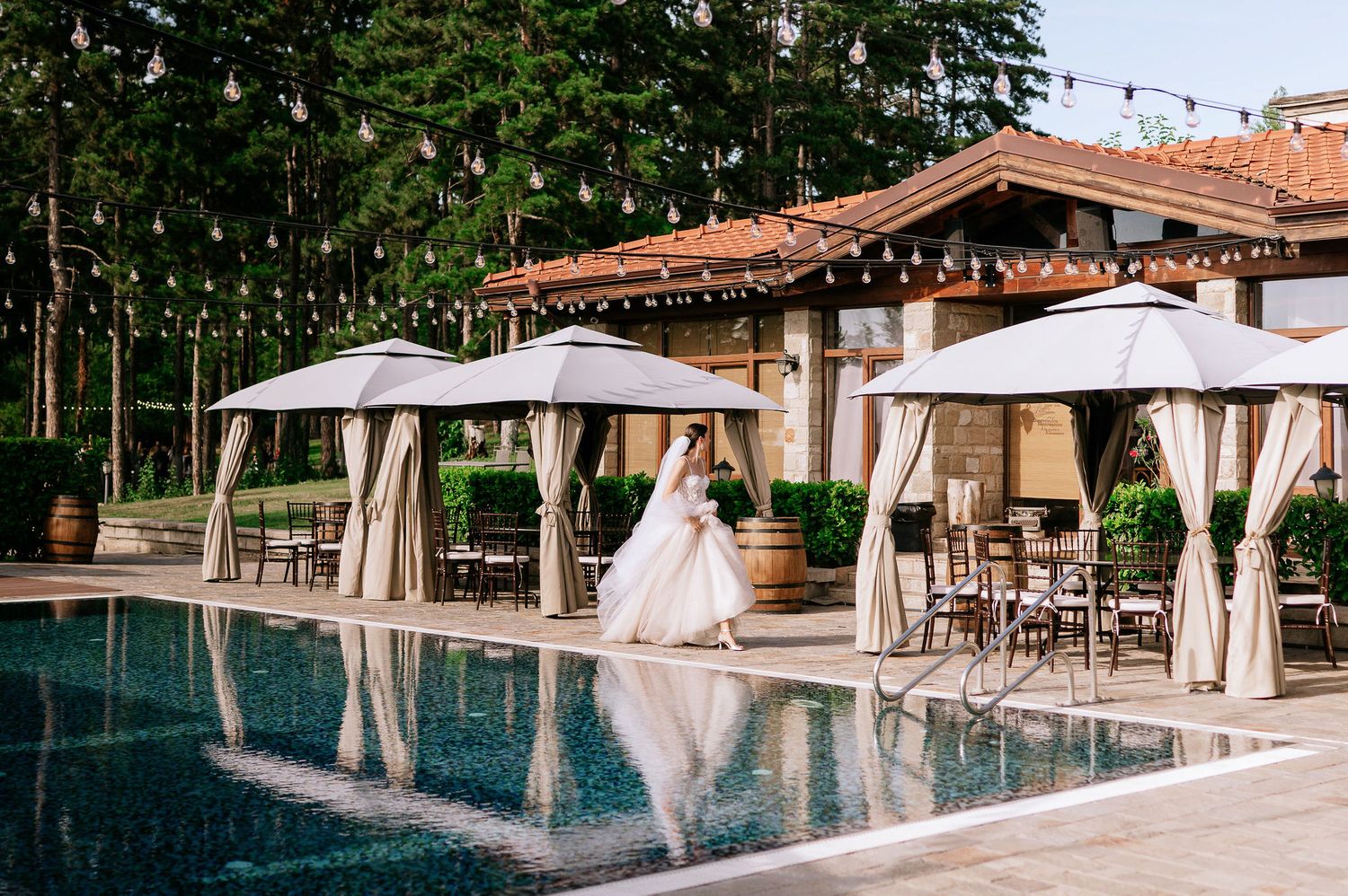 Outdoor pool area with string lights and white cabanas at a luxury venue.
