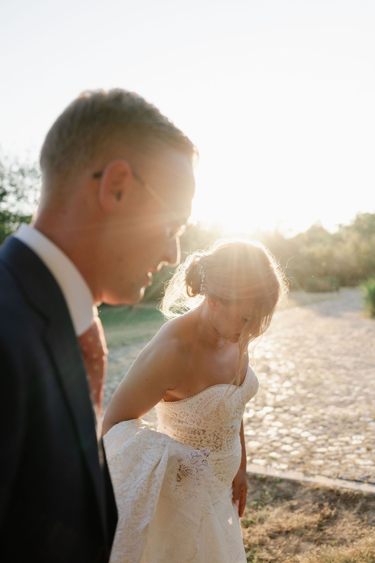 Intimate wedding moment captured in warm sunlight on a rustic path.