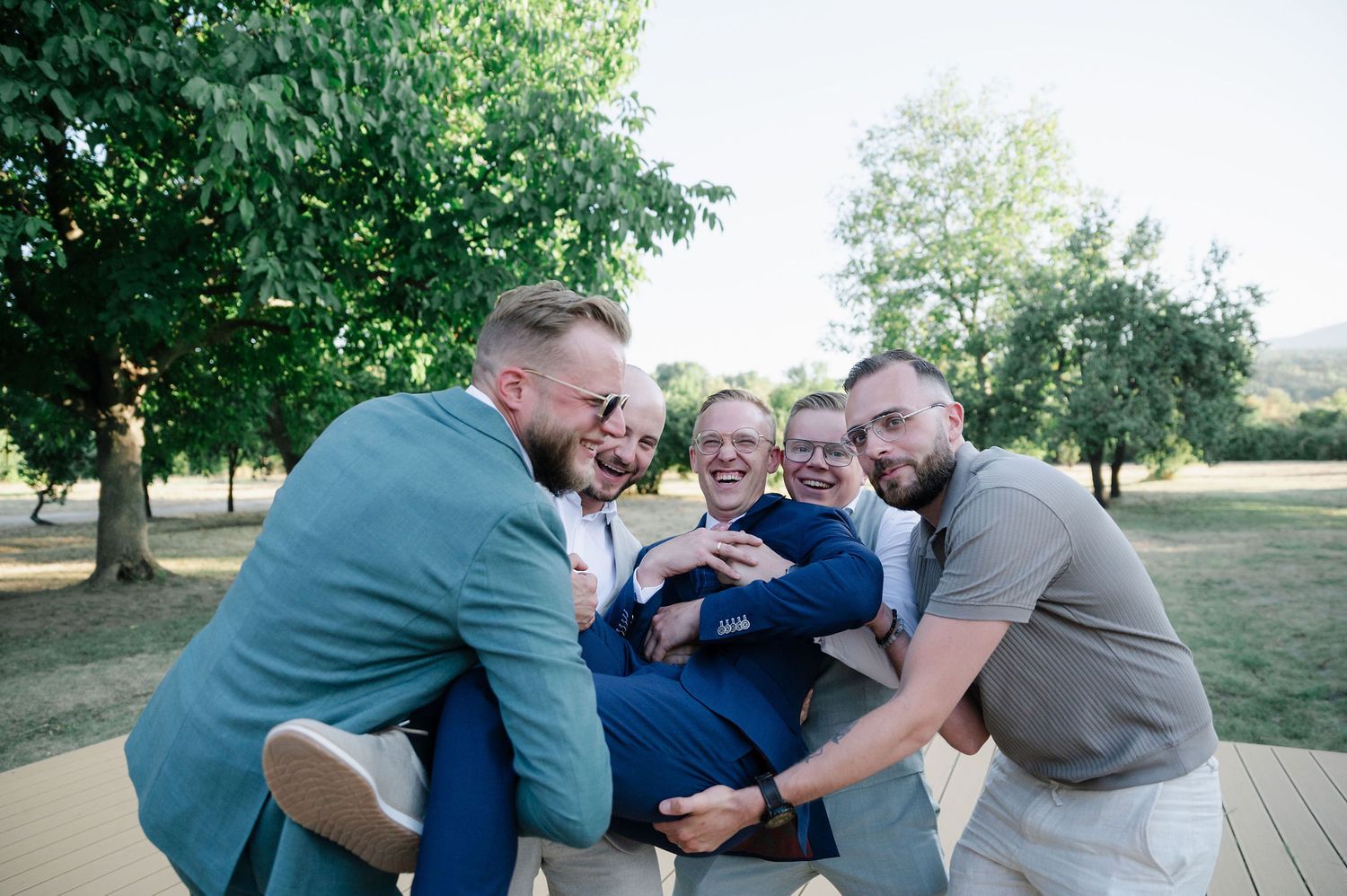 A group of people in formal attire huddled together playfully outdoors.