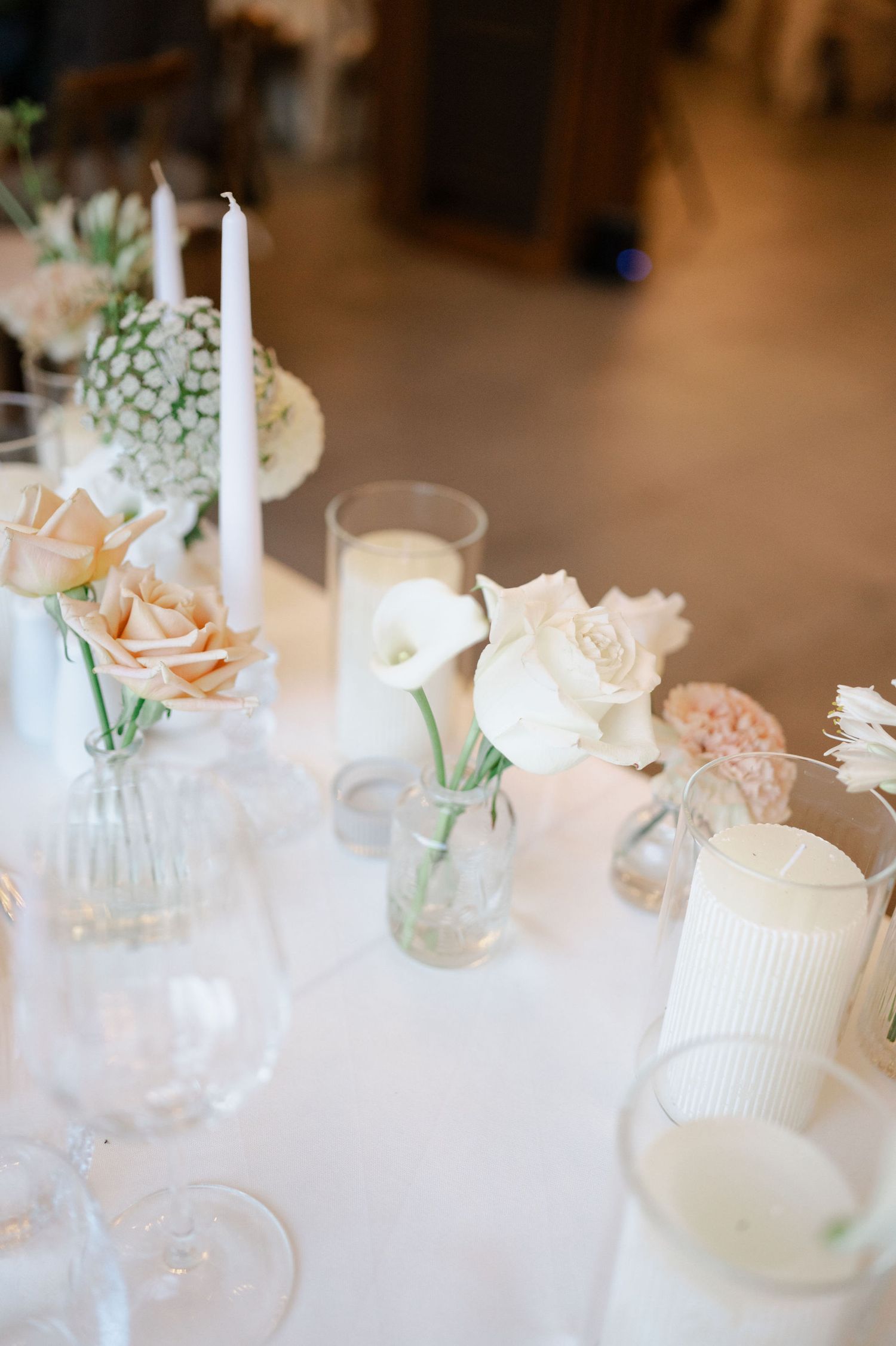 White candles and soft pink roses create a romantic tablescape with elegant glassware.