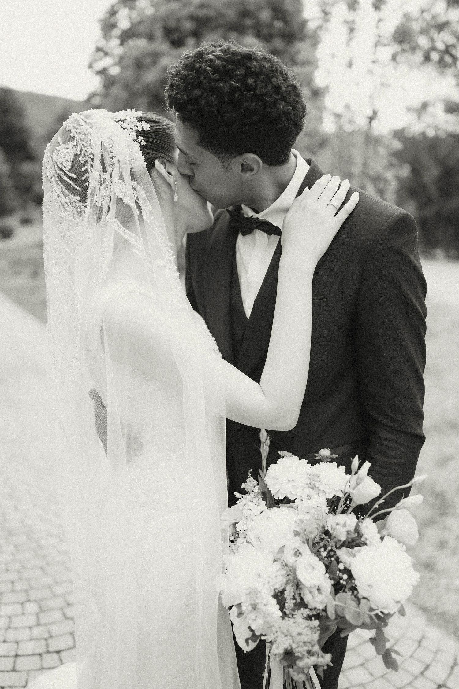 Black and white wedding portrait with elegant veil and bouquet details.