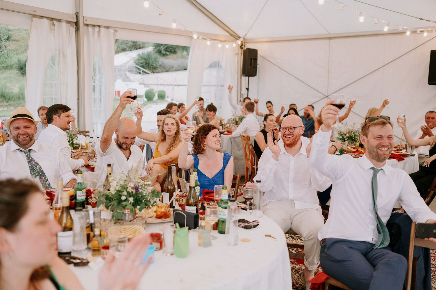 Energetic wedding reception scene with guests cheering and raising hands during celebrations.