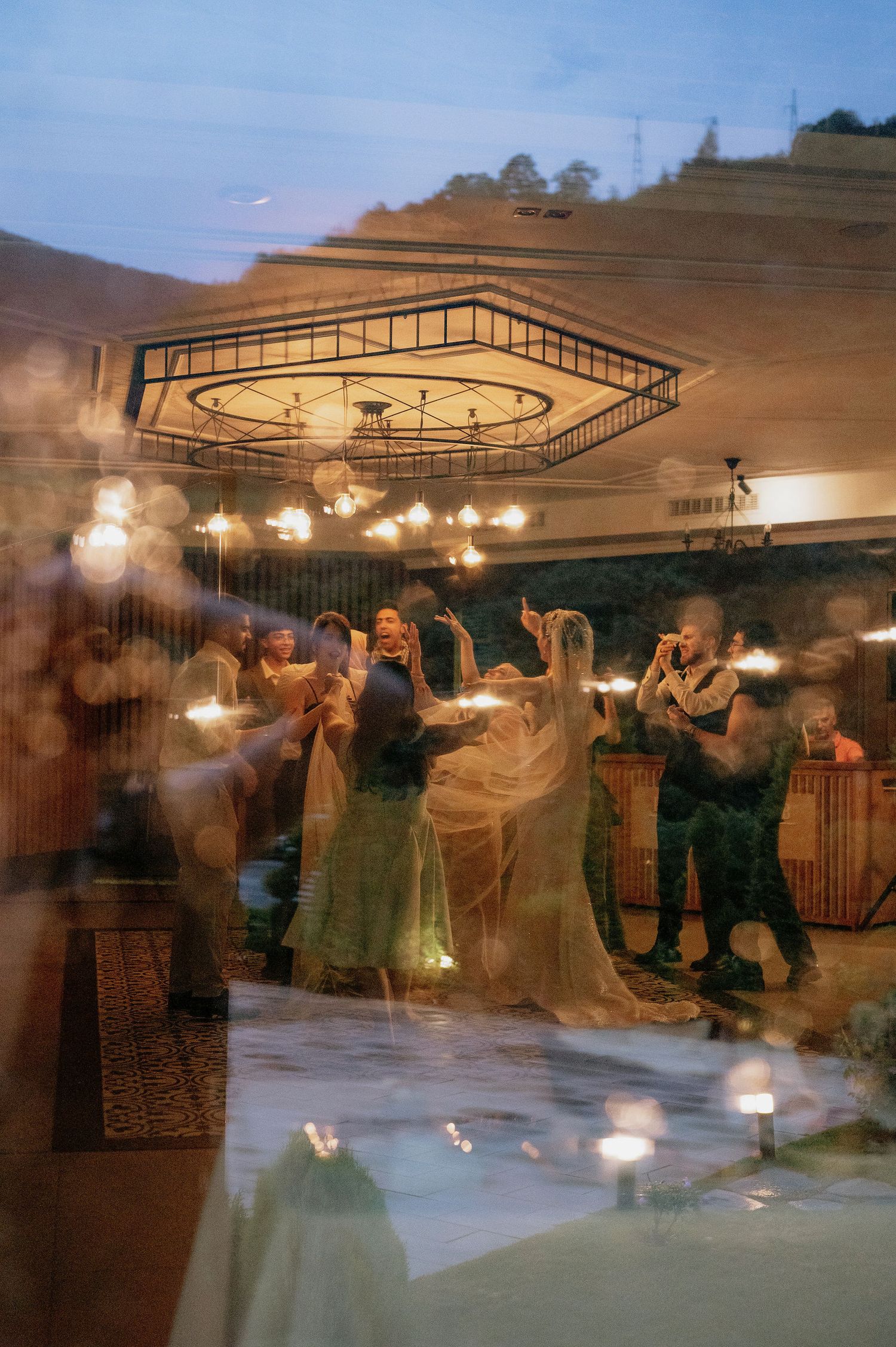 Time lapse photo captures dancing couples creating ghostly trails of movement under indoor lighting.
