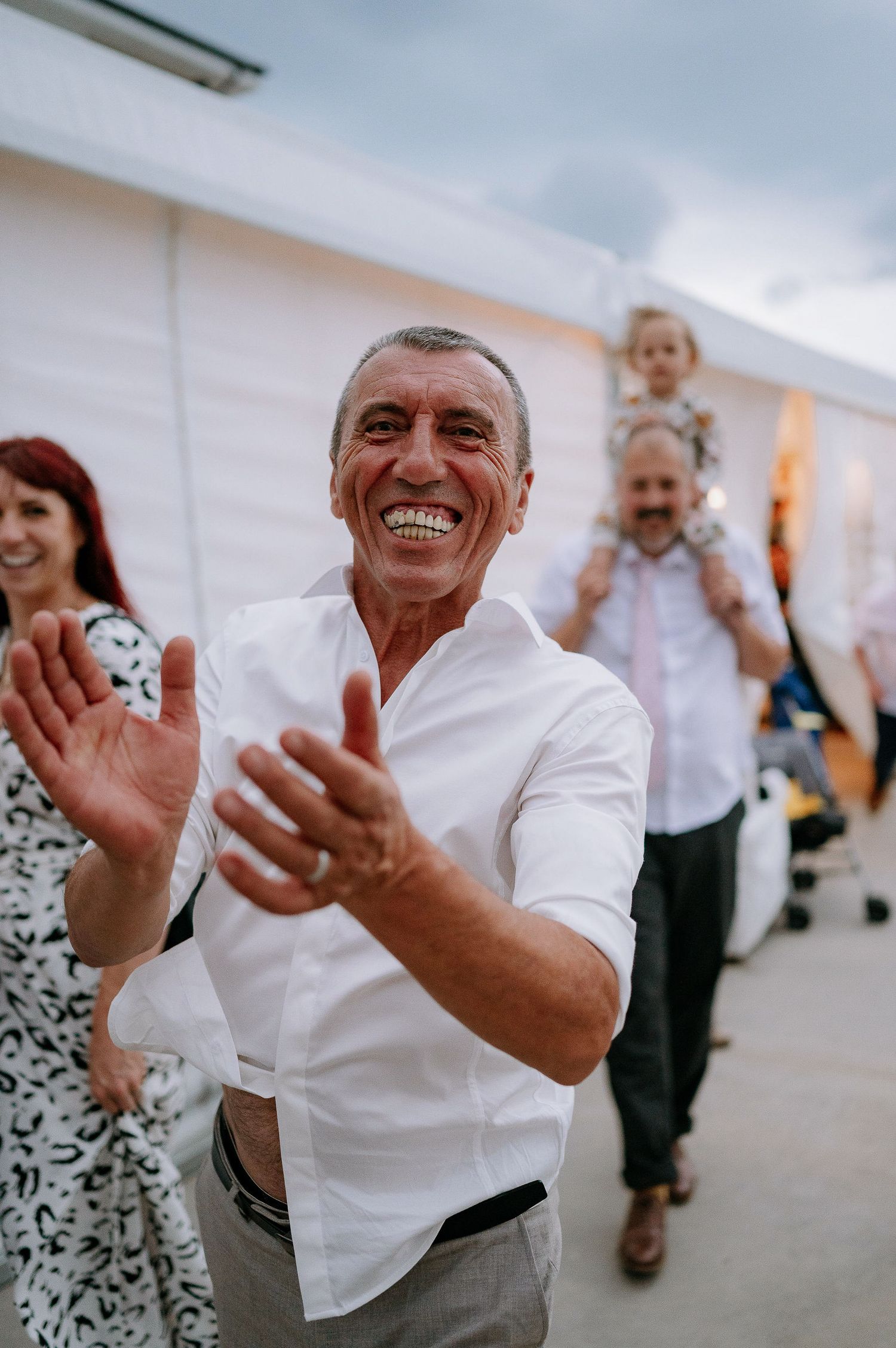 Joyful wedding guests dancing and celebrating at an outdoor reception.