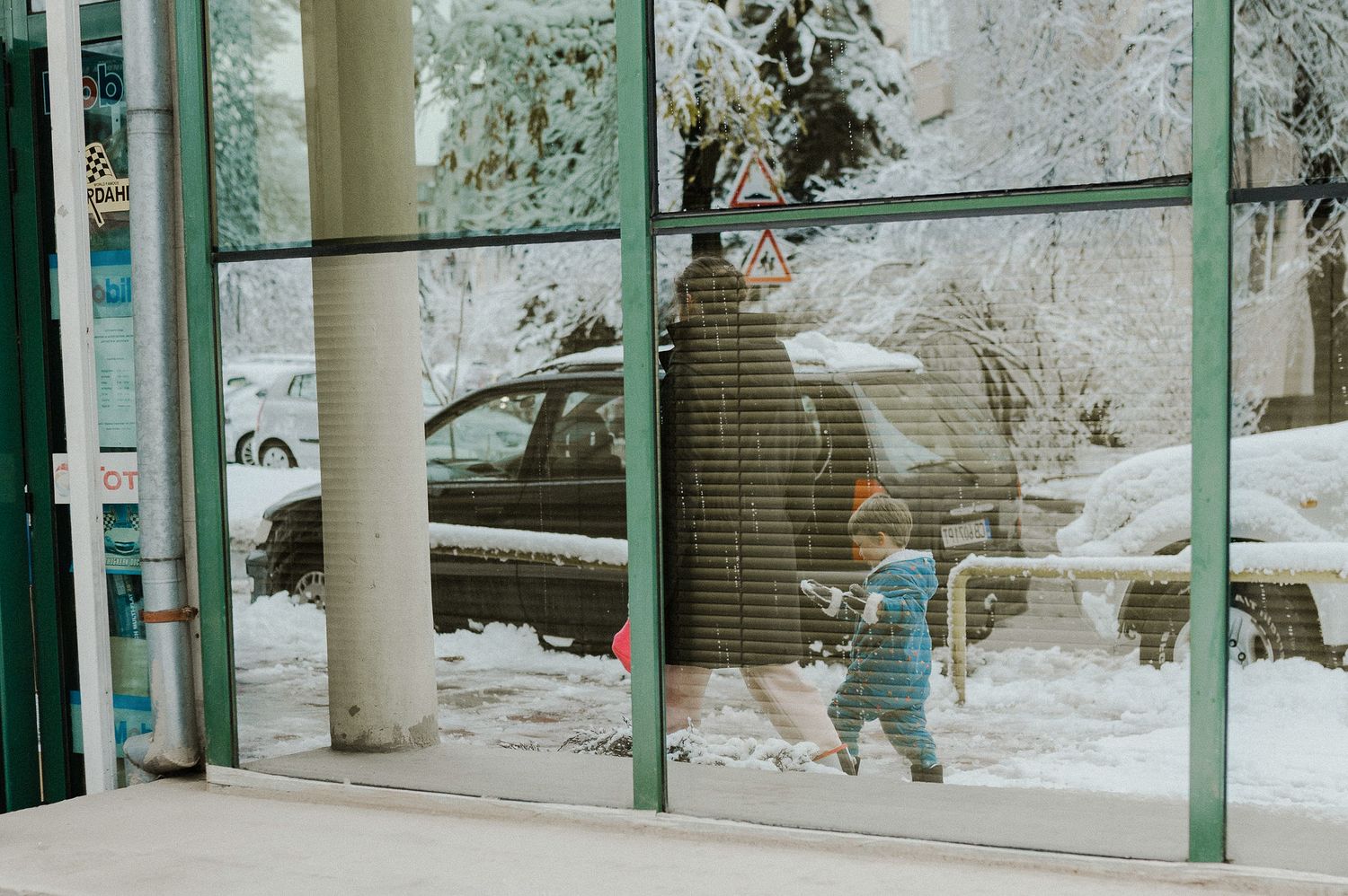 A snowy winter scene with white columns and green trim on a building exterior.