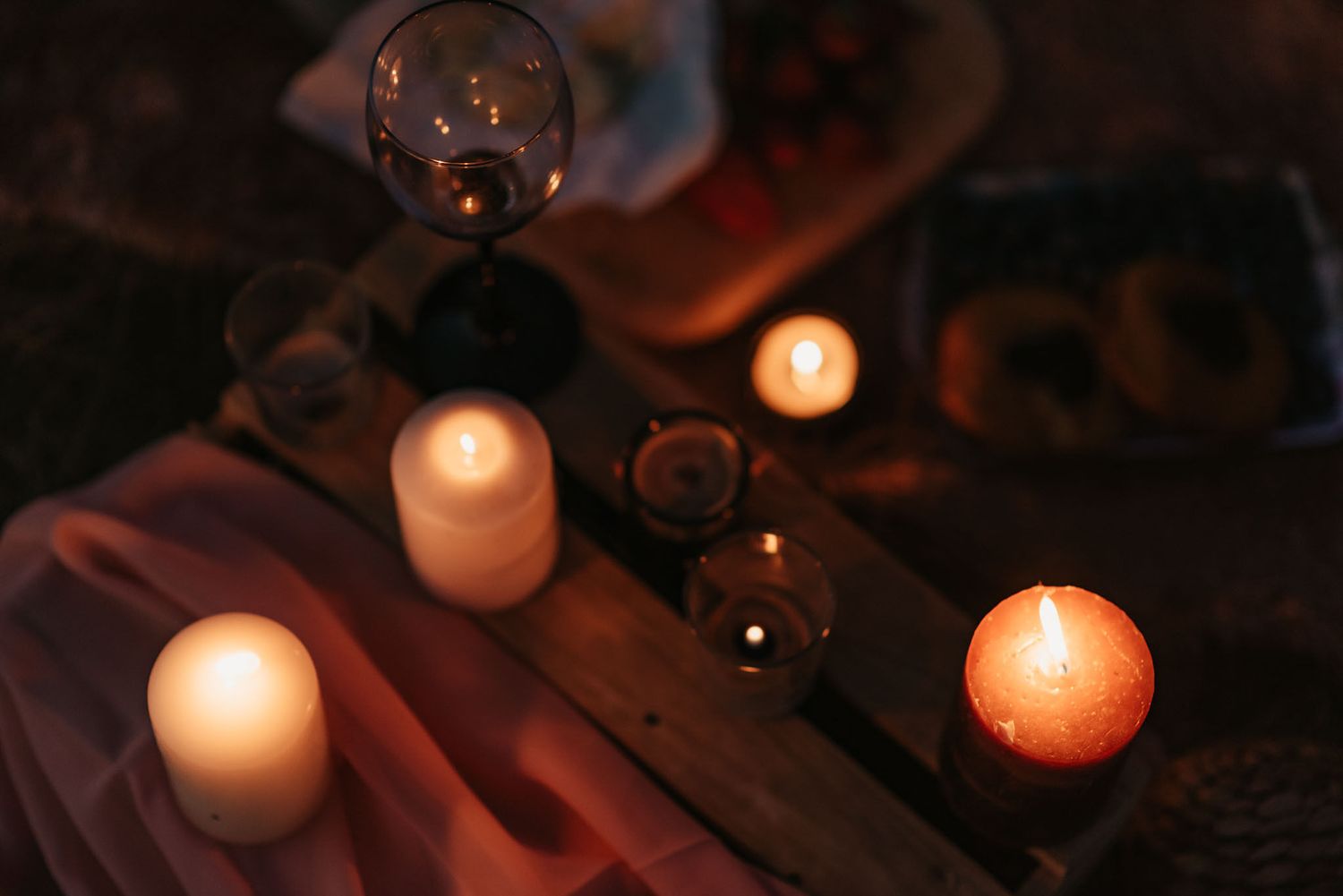 Glowing candles create intimate ambiance on a dark wooden surface.