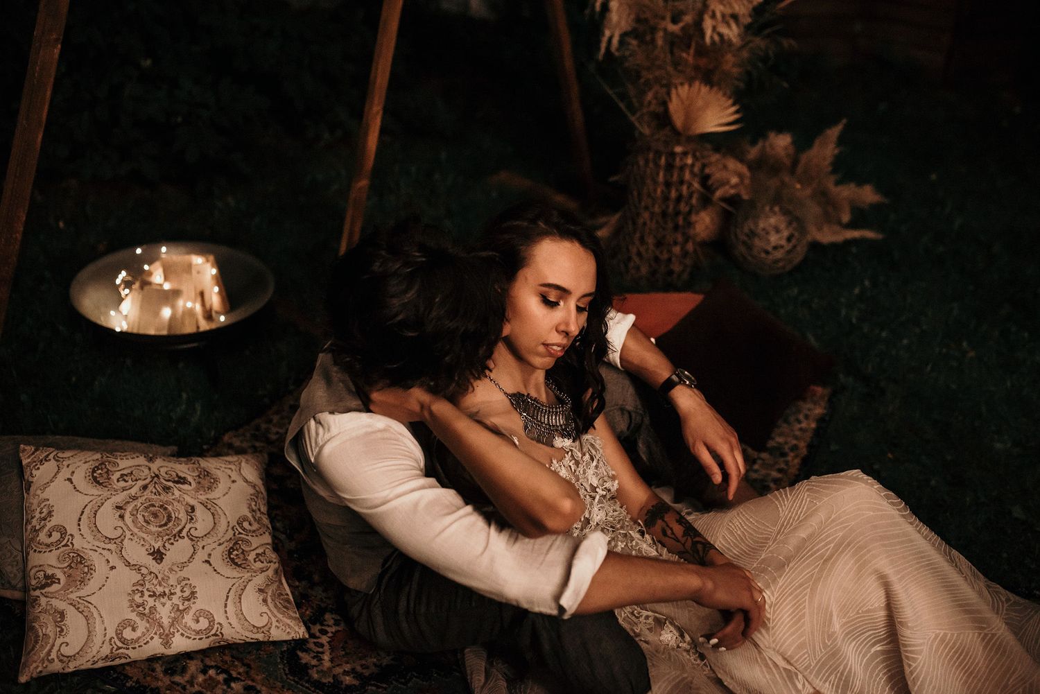 A couple in wedding attire dances together in a dimly lit room with romantic lighting and decor.