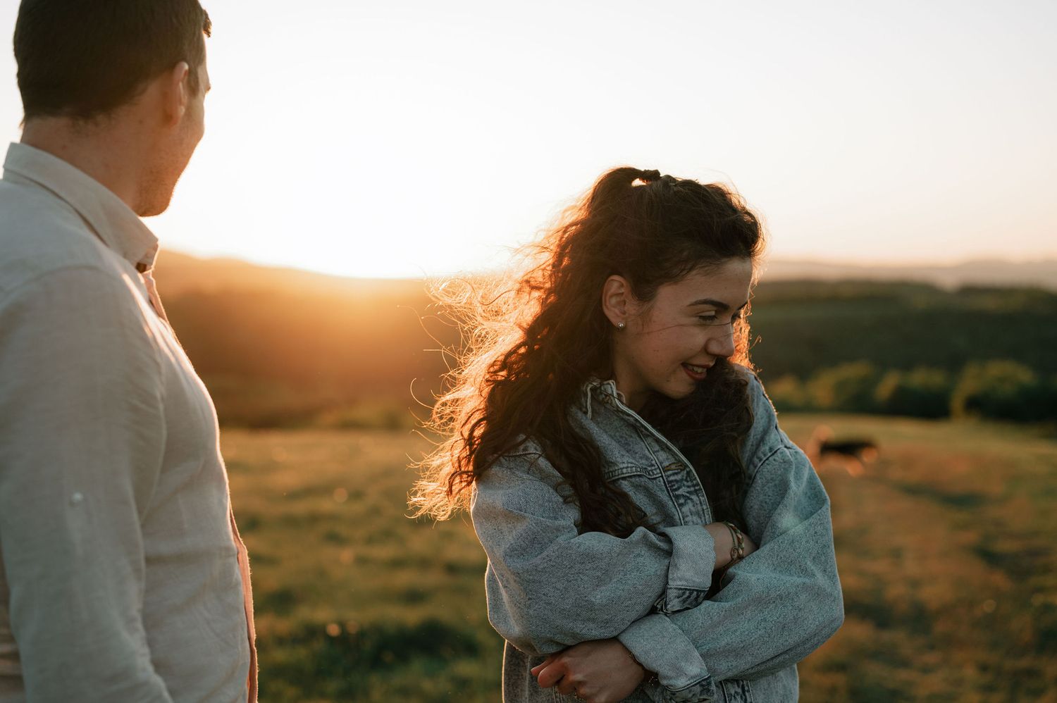 A couple embraces in a golden field at sunset creating a romantic silhouette against the warm sky.