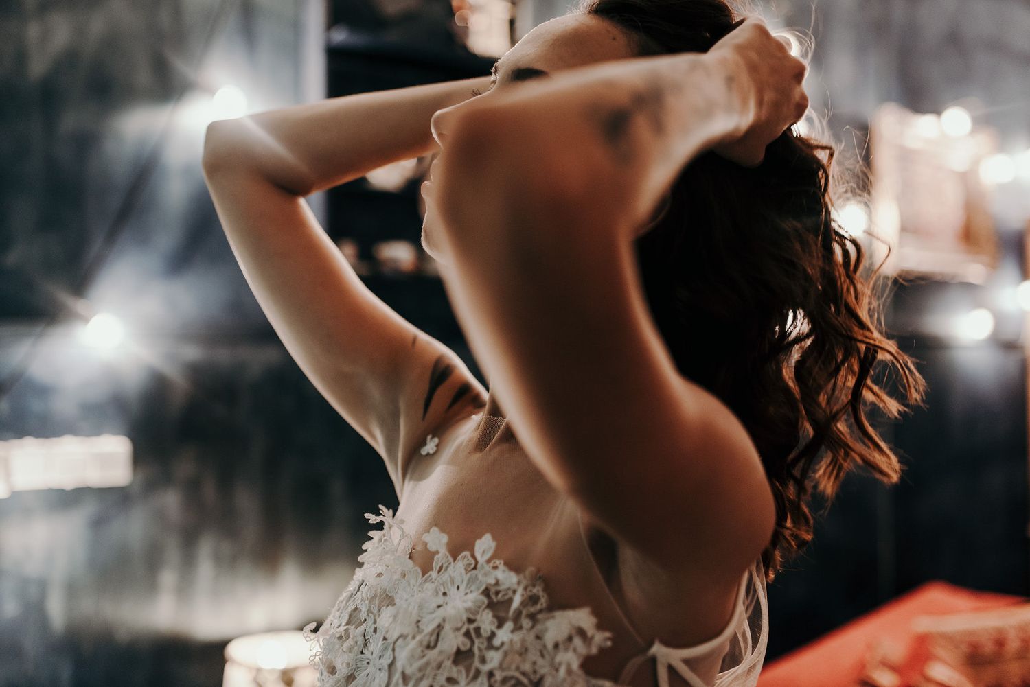 Artistic bridal portrait series showing delicate details of a wedding dress in moody lighting.