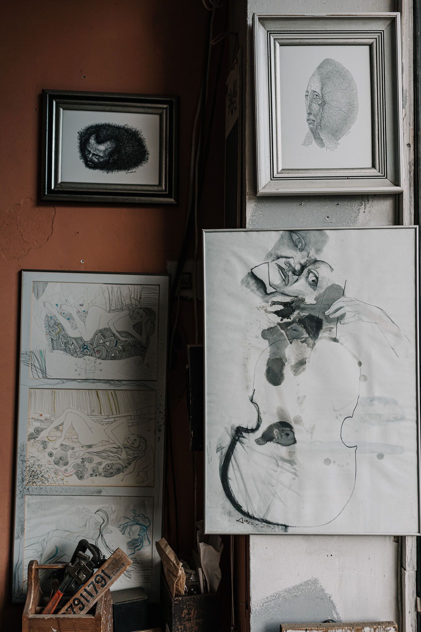 Gallery wall displaying black and white sketches and portraits in simple frames.
