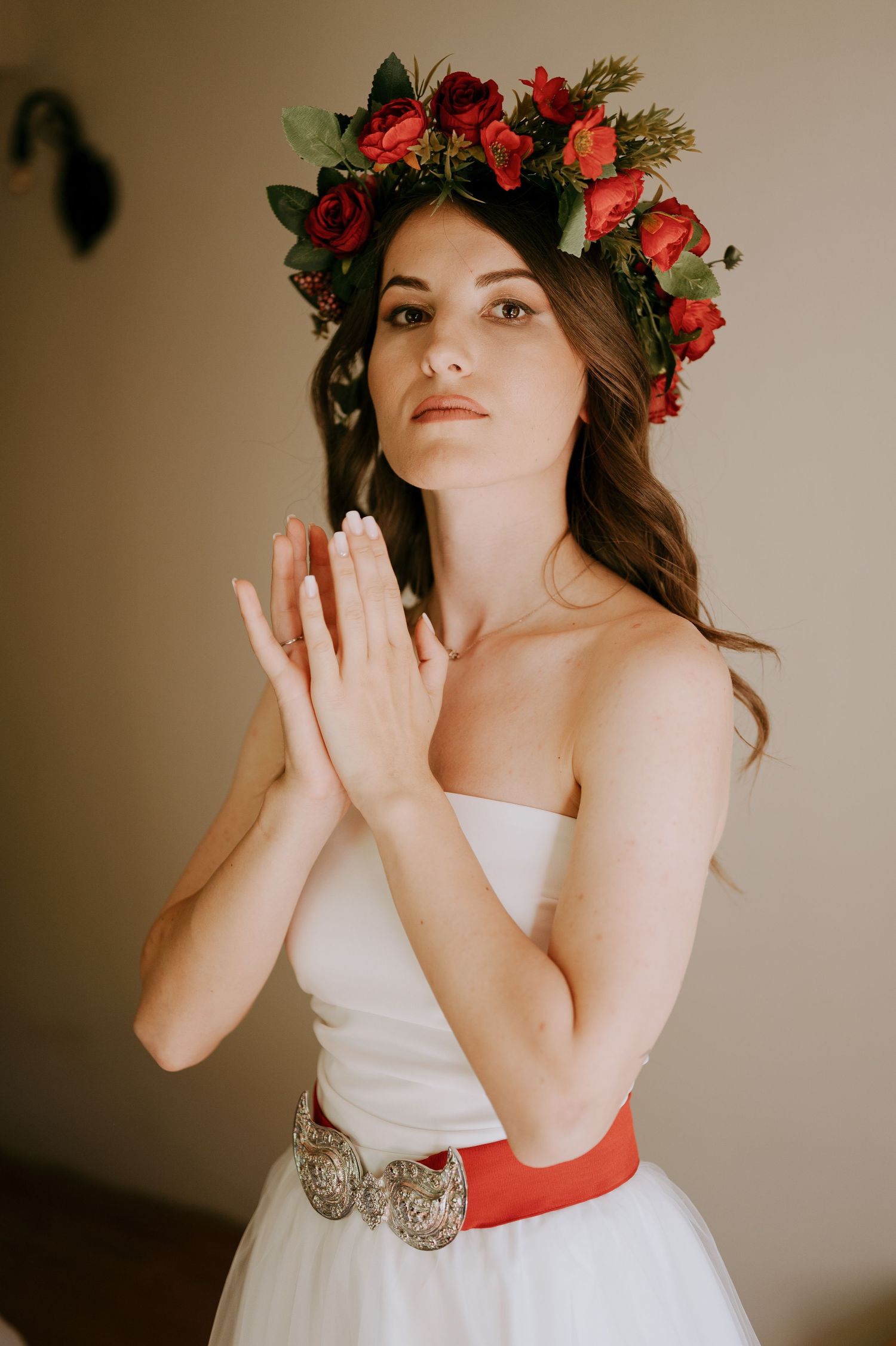Expressive bridal portrait series showing white gown with red details and rose crown.