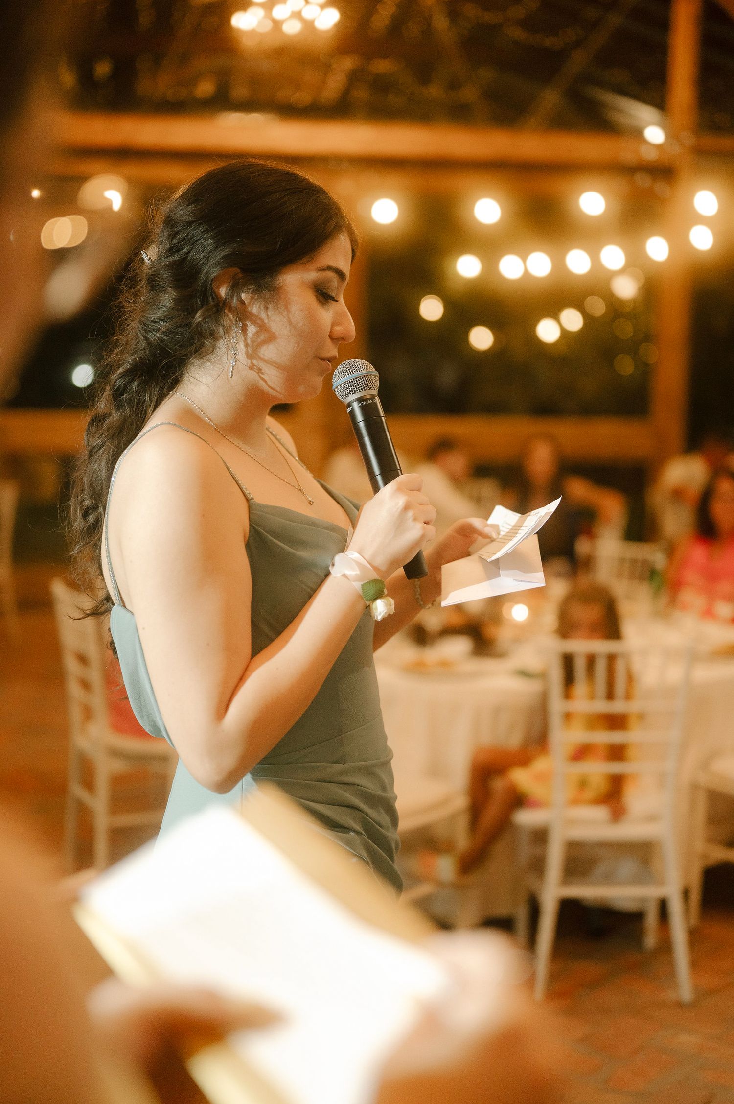 A series of five photos showing someone giving a heartfelt speech at an indoor event with warm lighting and string lights.