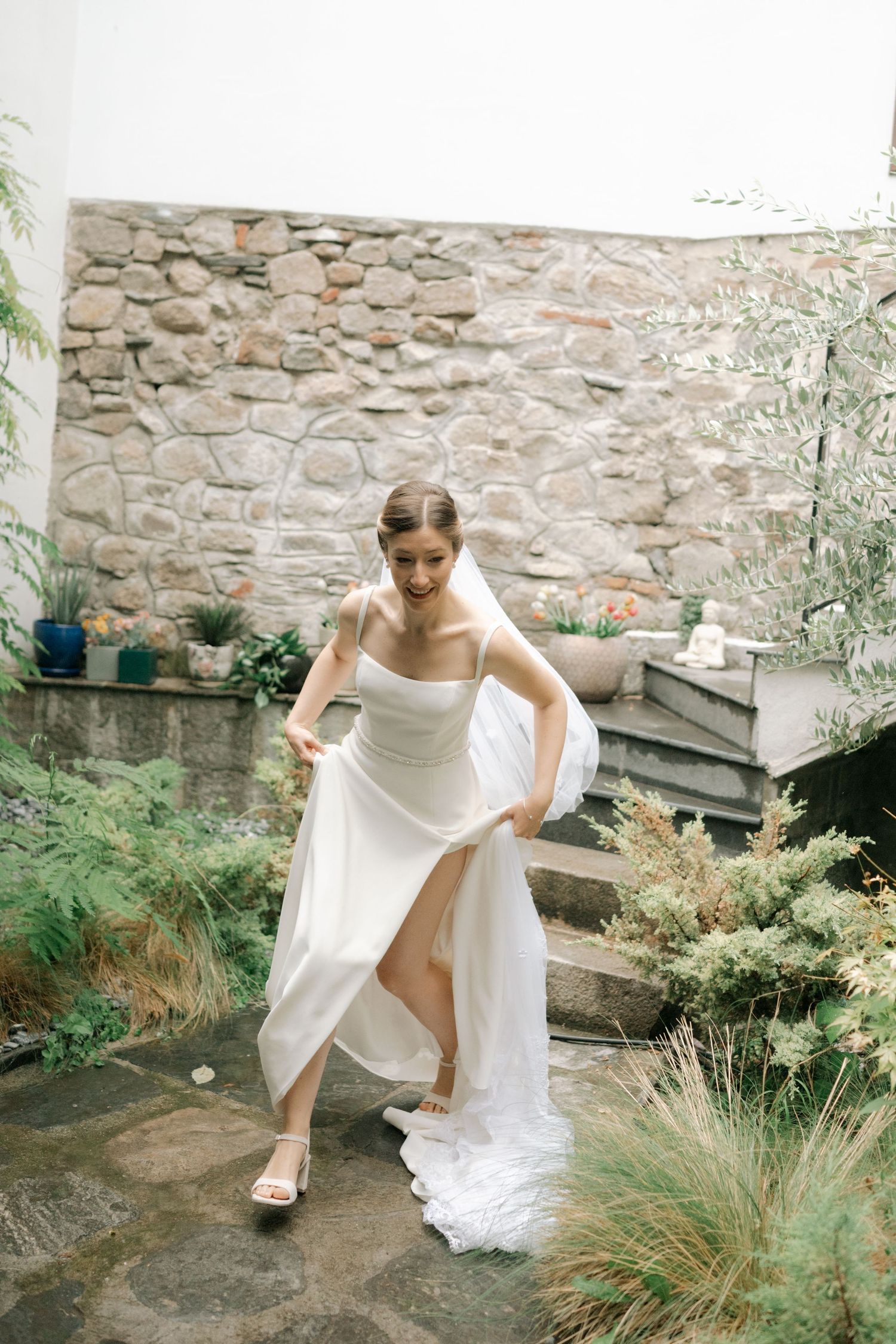A series of graceful movements in a white dress against a stone wall backdrop.