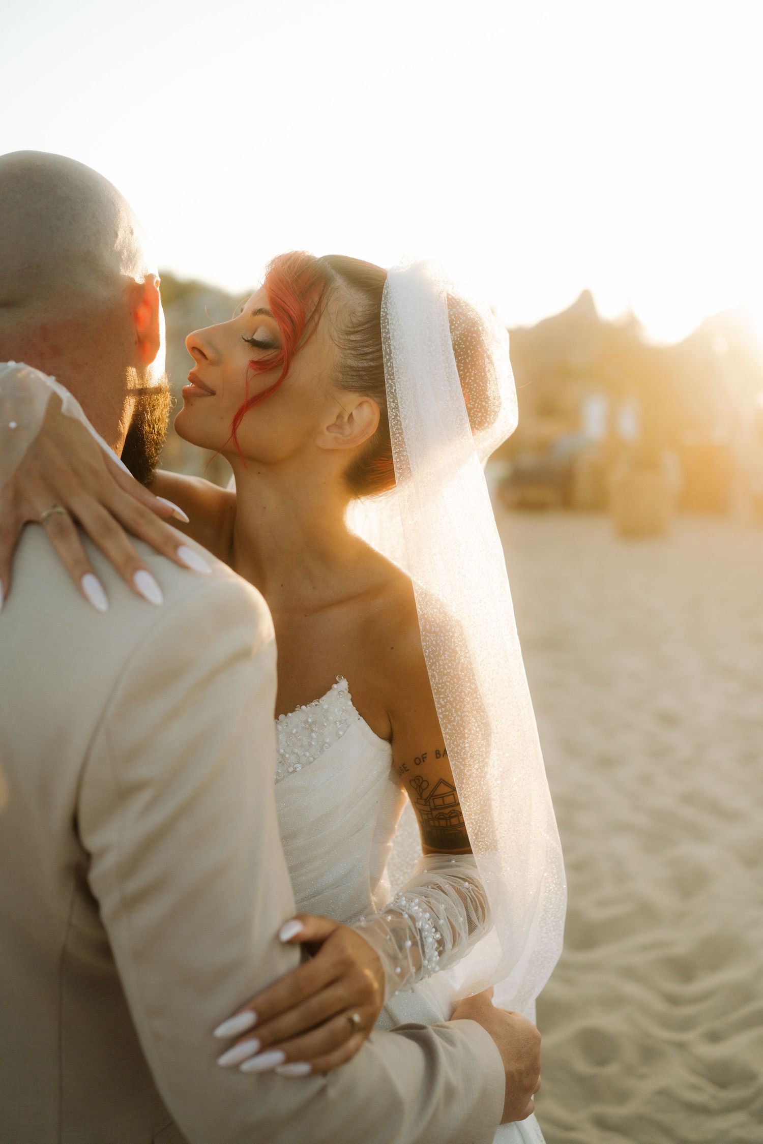 Romantic couple embraces on sandy beach during golden sunset hour.