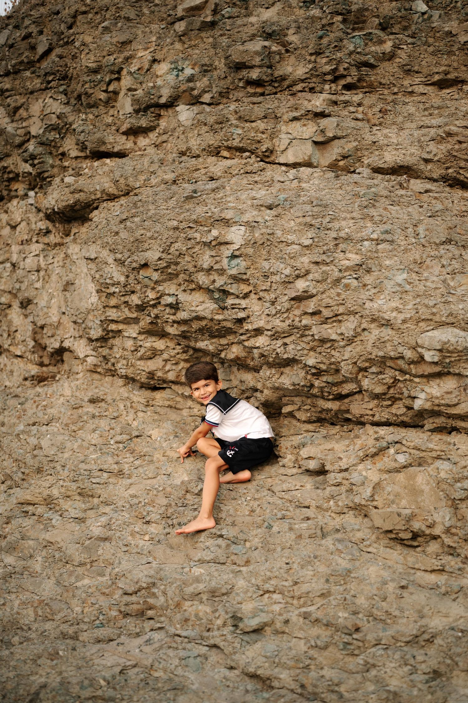 Rock climber scales steep limestone cliff face using advanced bouldering techniques and minimal gear.