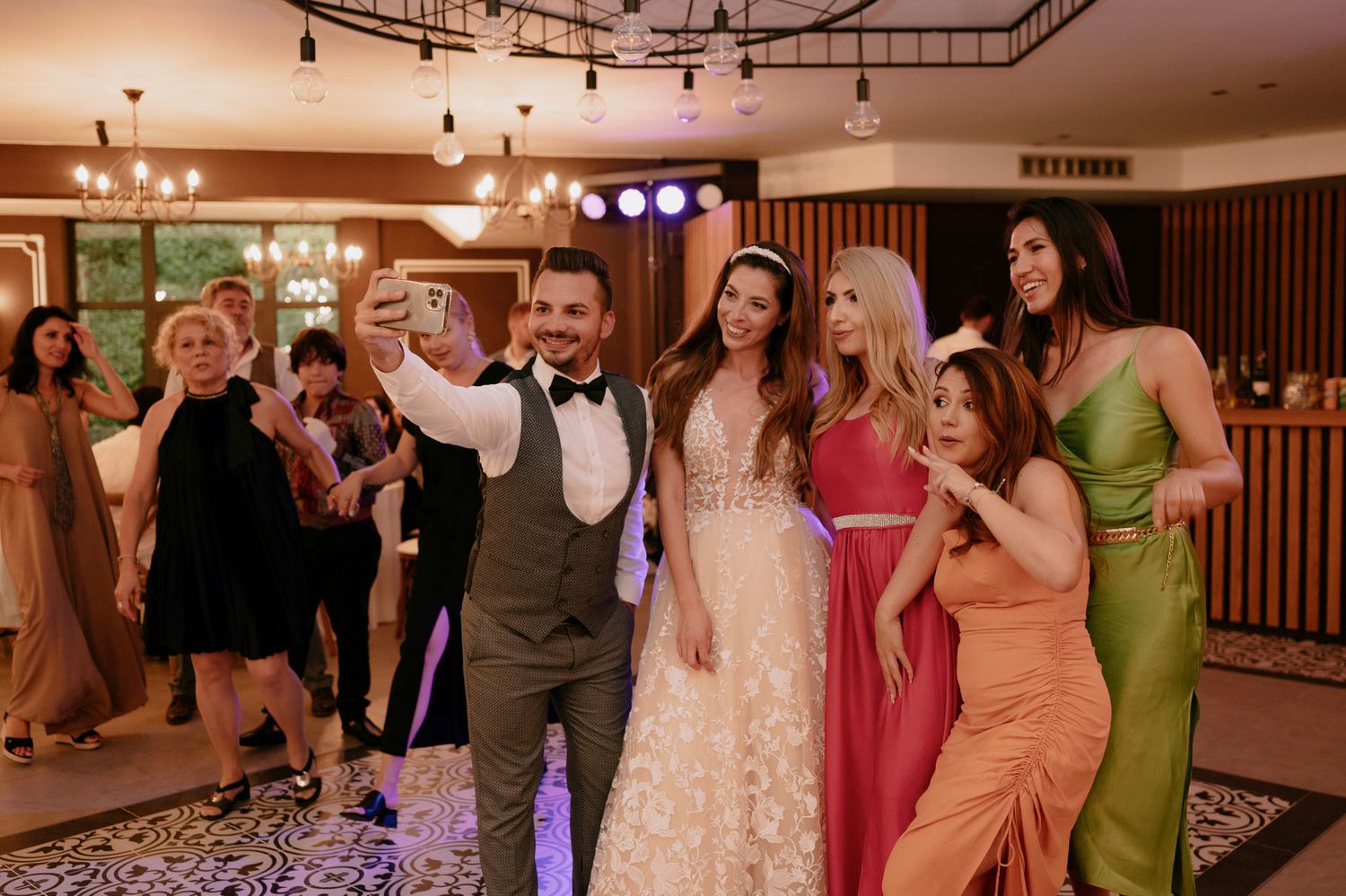 Wedding guests dance and celebrate together on a ballroom dance floor during an evening reception.