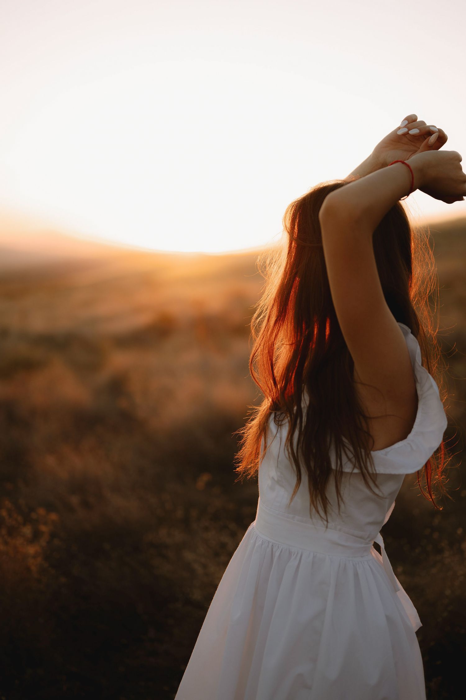 A person in a flowing white dress twirls gracefully in a golden sunset field, creating a dreamy silhouette.
