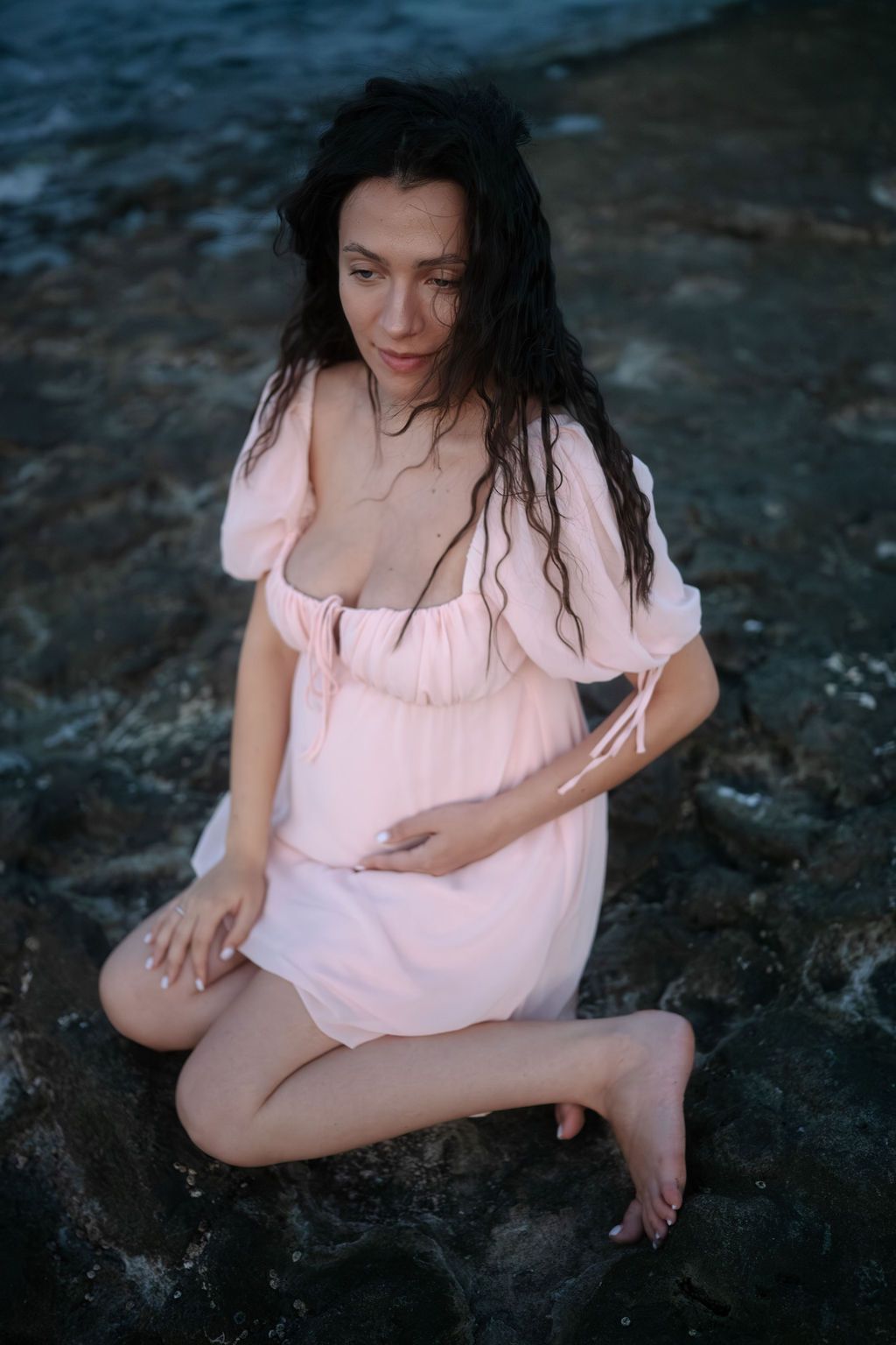 A person in flowing pink attire poses gracefully against a dark rocky backdrop in an artistic series.
