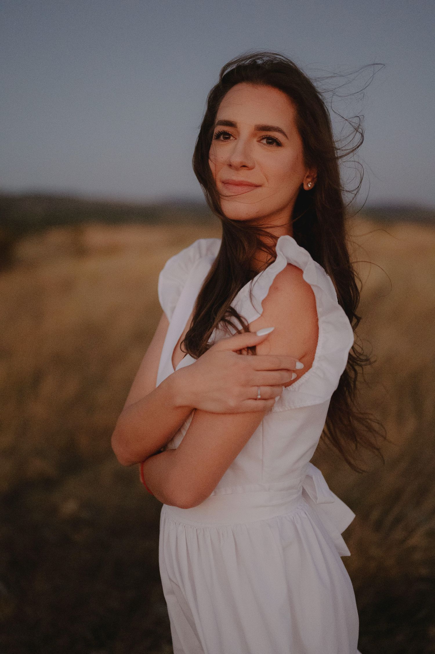 A series of dreamy outdoor portraits showing a woman in a white dress standing in a golden field at sunset.