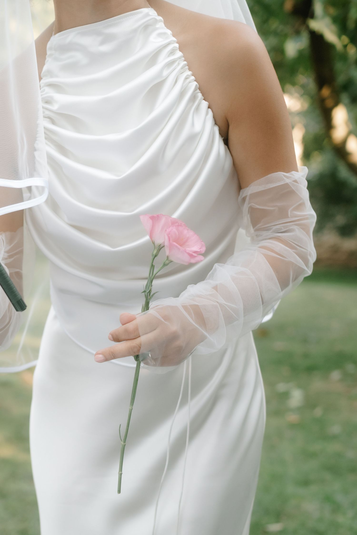 Close-up sequence of hands in sheer white gloves delicately holding a pink rose stem against a white wedding dress.