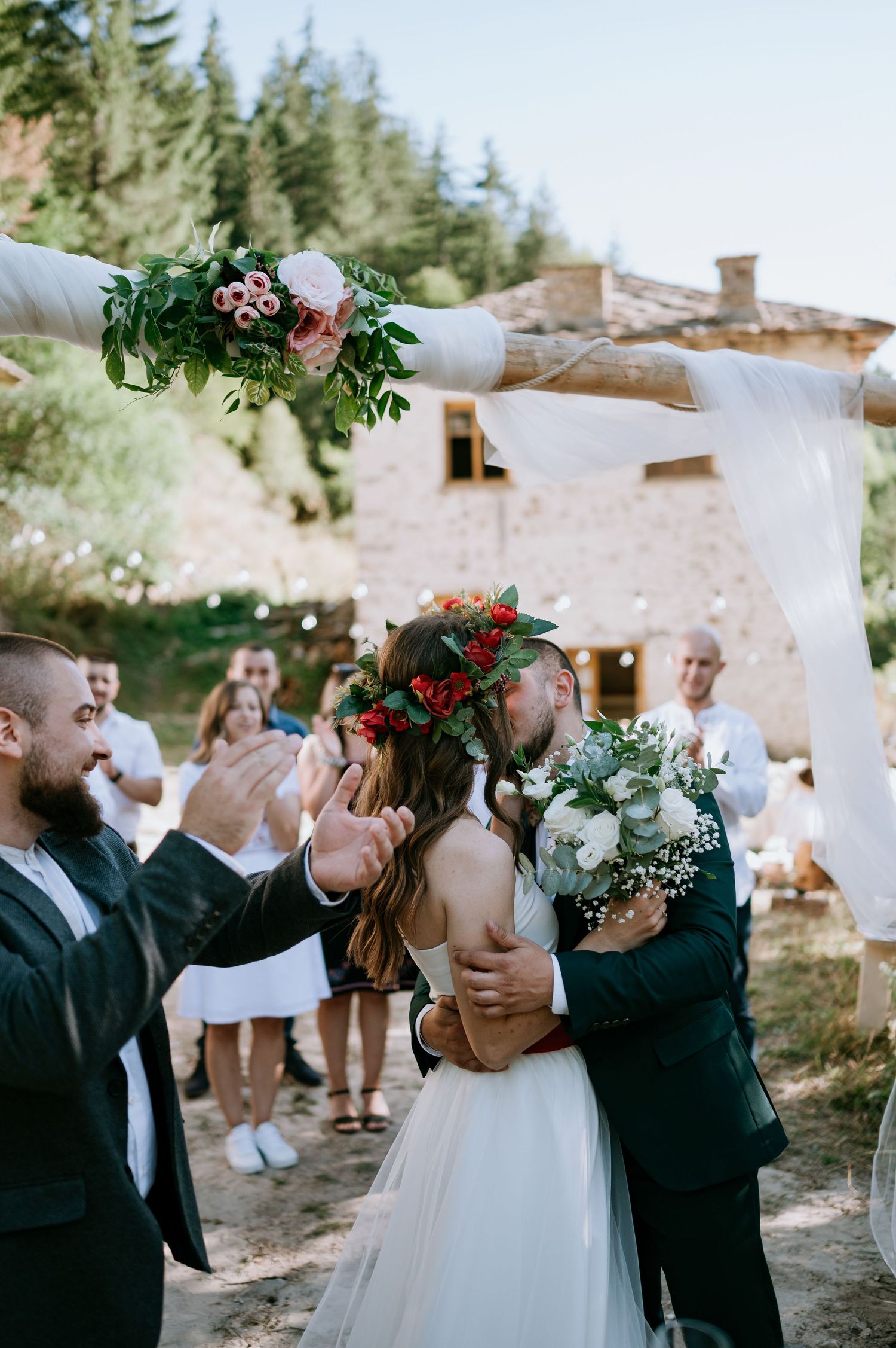 Wedding celebration with guests cheering in rustic outdoor setting with white drapery.