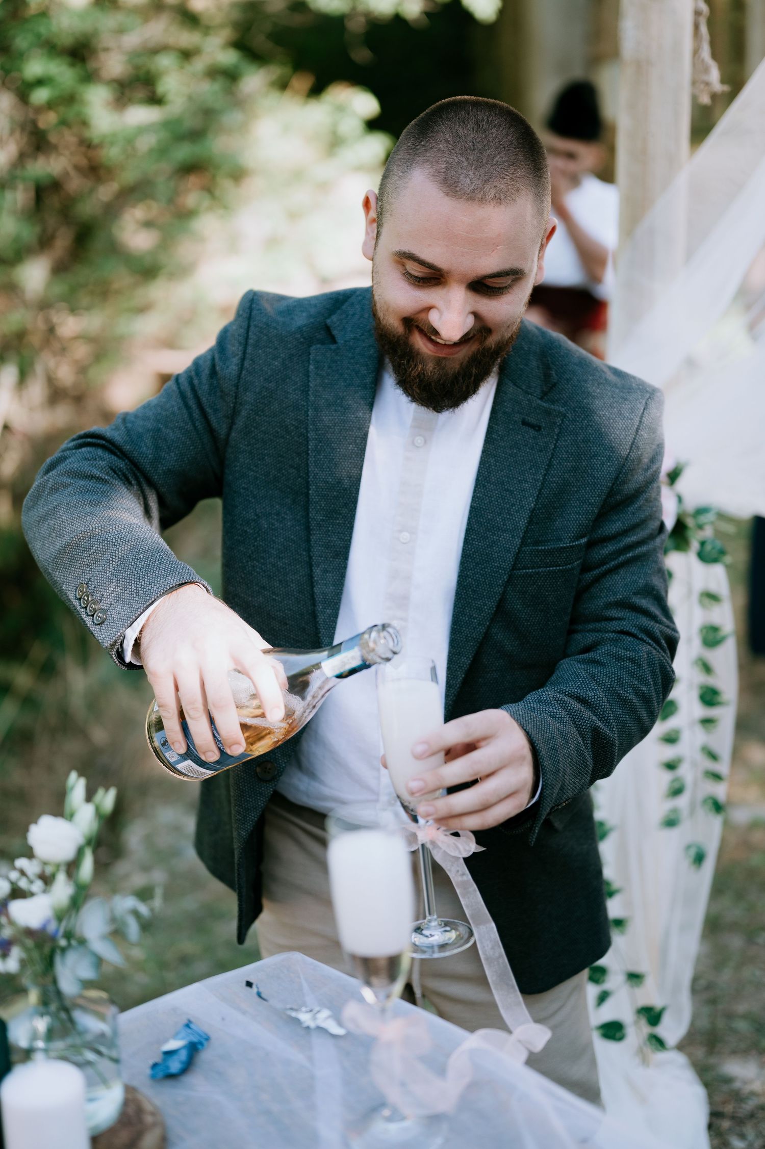 Close-up sequence showing someone in a dark blazer pouring a beverage at an outdoor event.