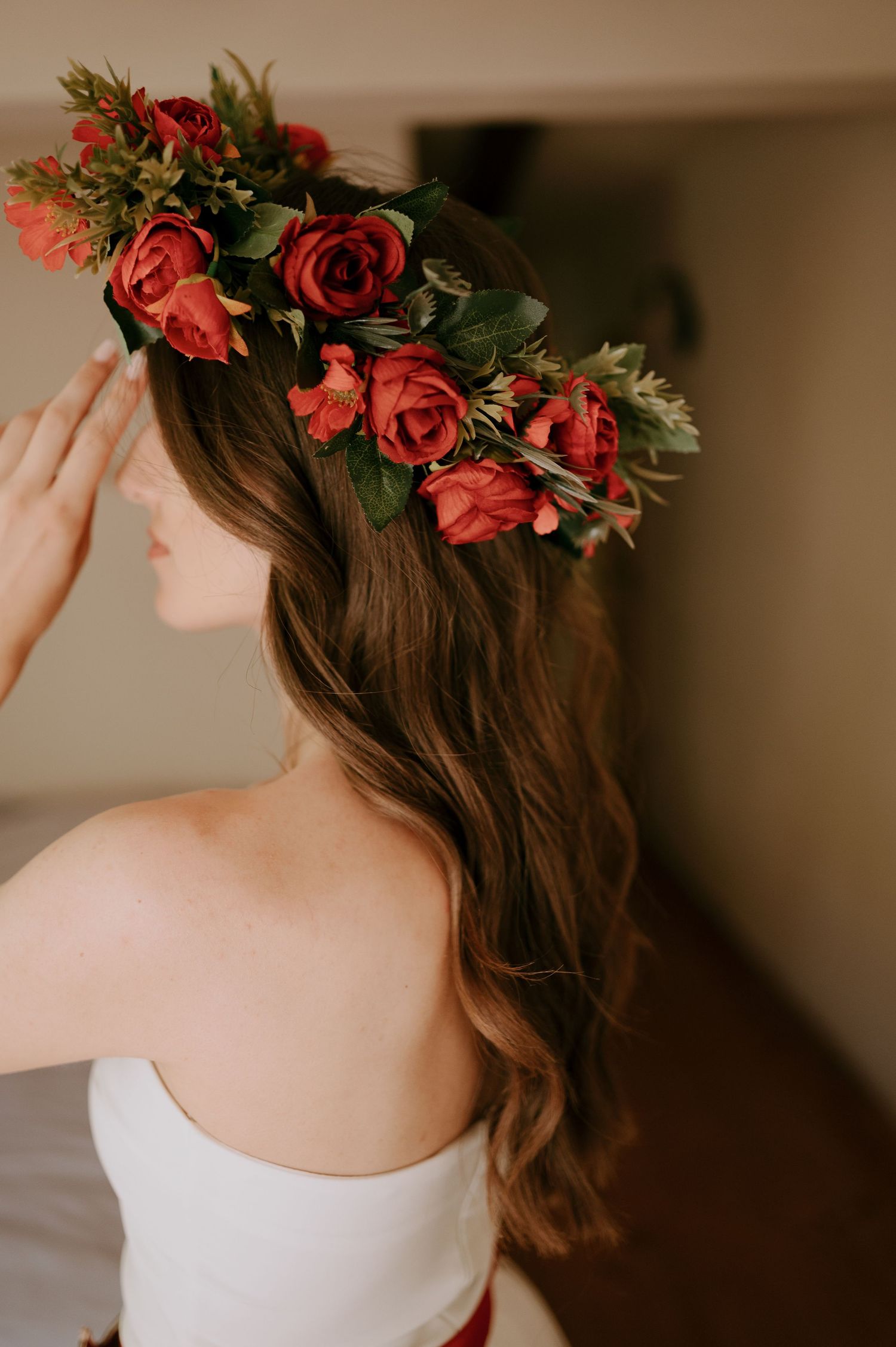 Elegant floral crown with coral roses sits atop wavy brown hair.