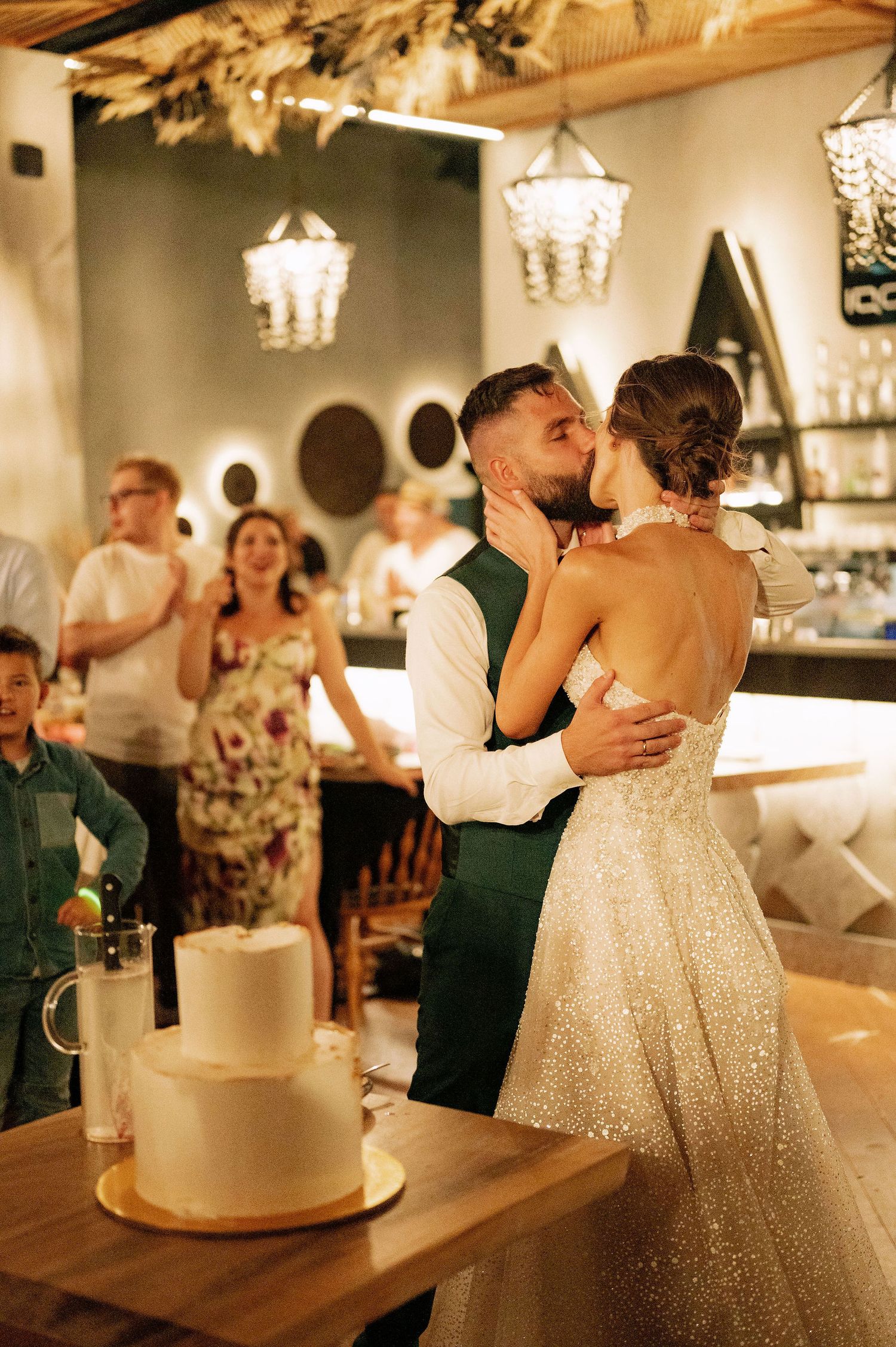 Intimate dance moment at a wedding reception with a white tiered cake in the foreground.