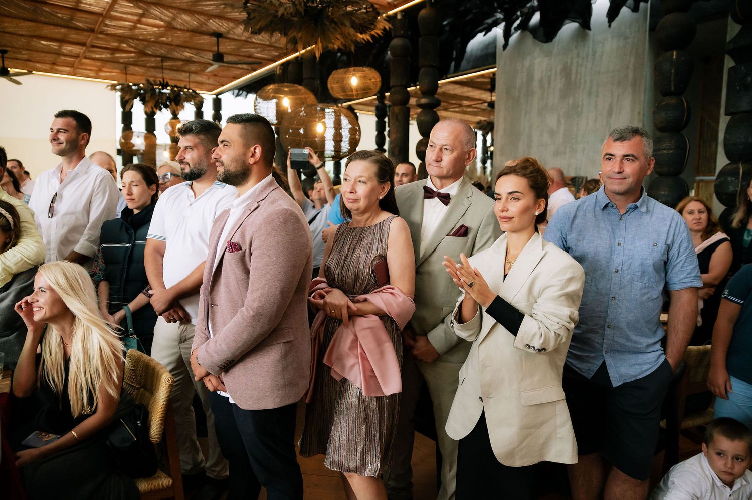 Guests celebrate during wedding reception in a rustic industrial venue with mood lighting.