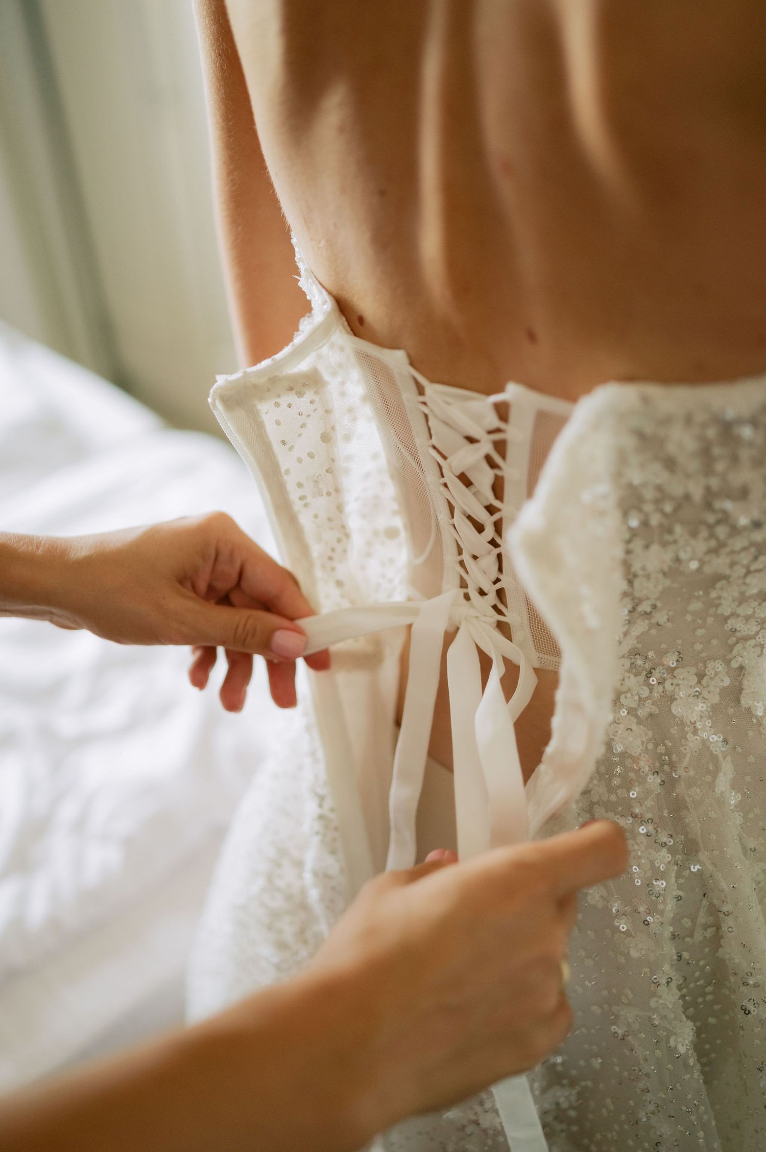 Detailed view of wedding dress lacing being adjusted.