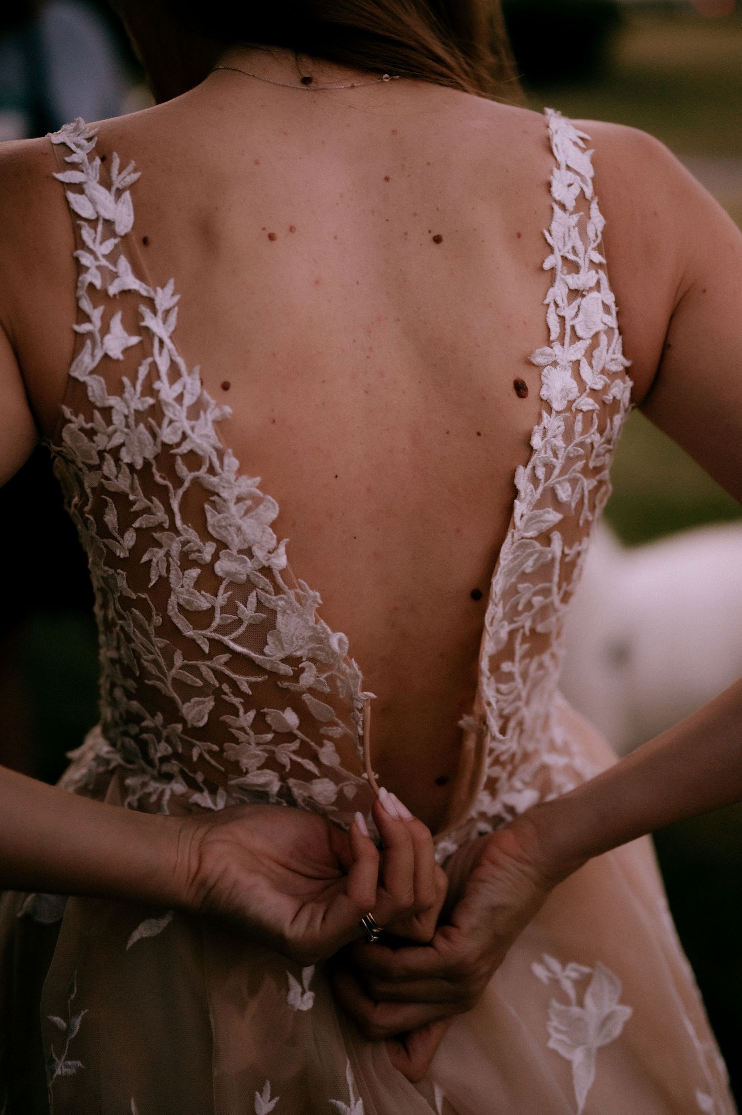 Back view of a wedding dress showing intricate white lace details and floral appliques.