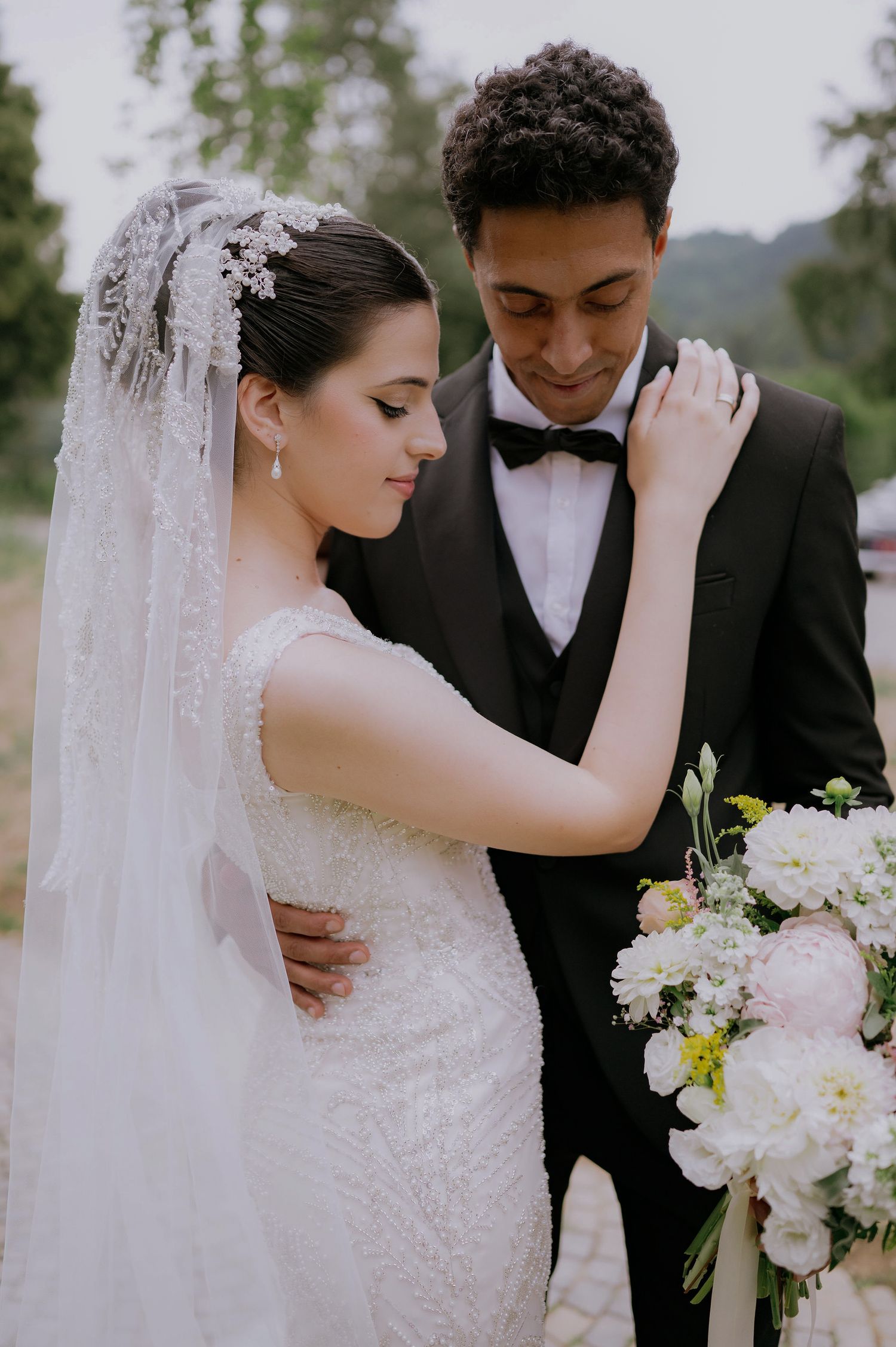 Tender wedding moment captured with elegant veil and white floral bouquet.