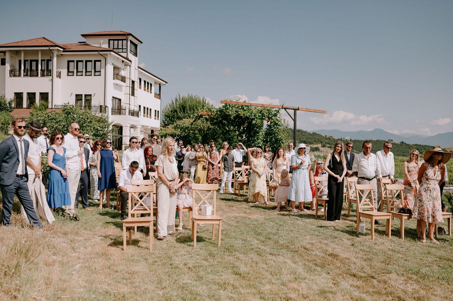 Outdoor wedding ceremony setup with wooden chairs and mountain backdrop.