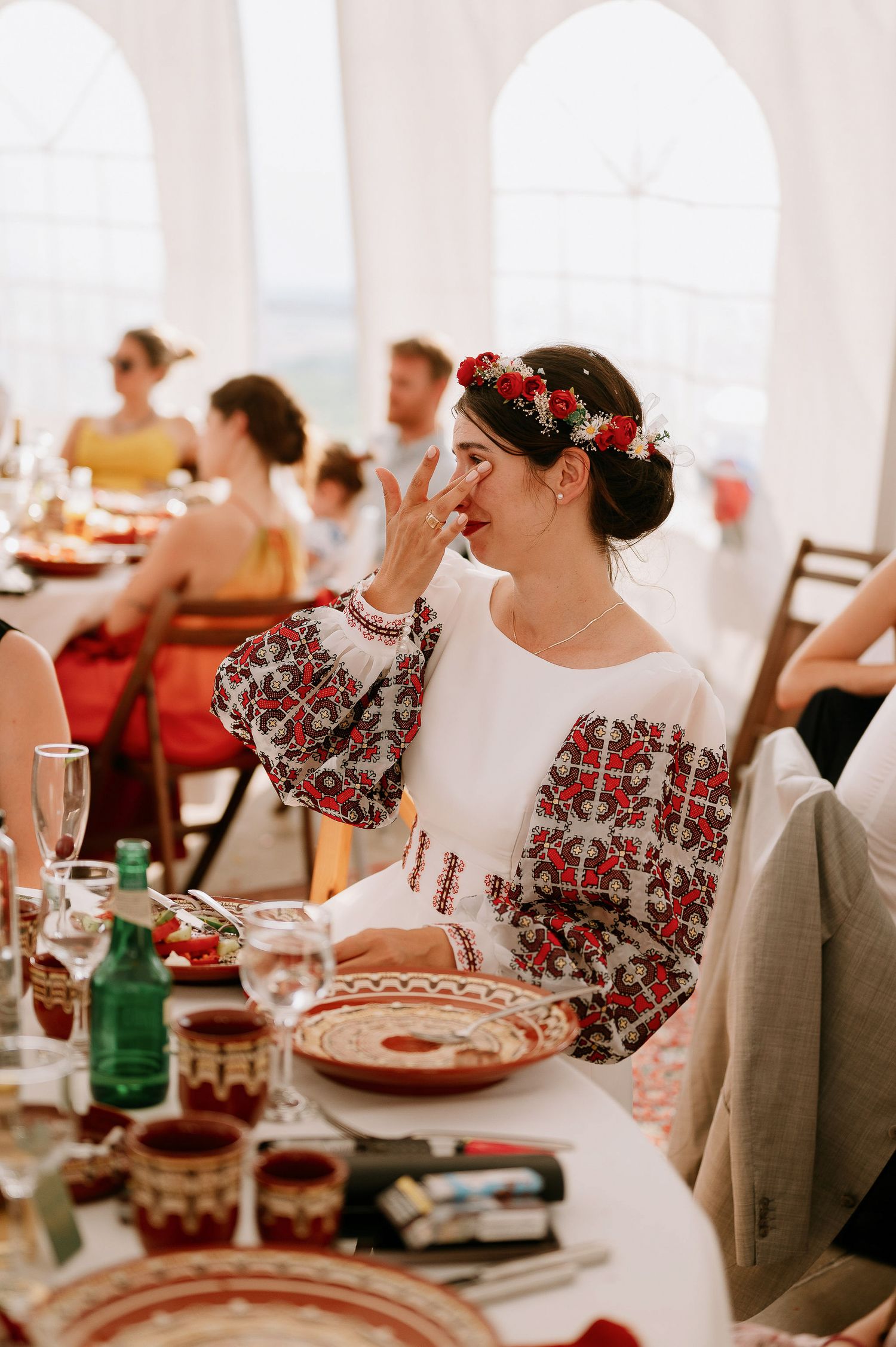 Guests in folk-inspired dresses enjoying a festive wedding reception meal.