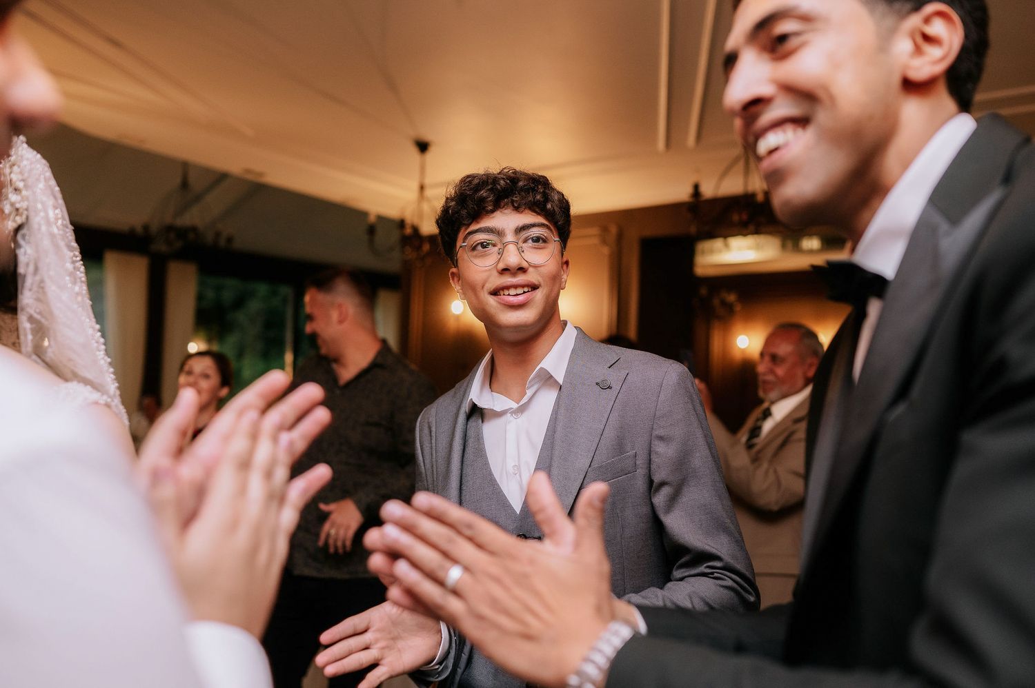 Guests laughing and enjoying themselves during a wedding celebration indoors.