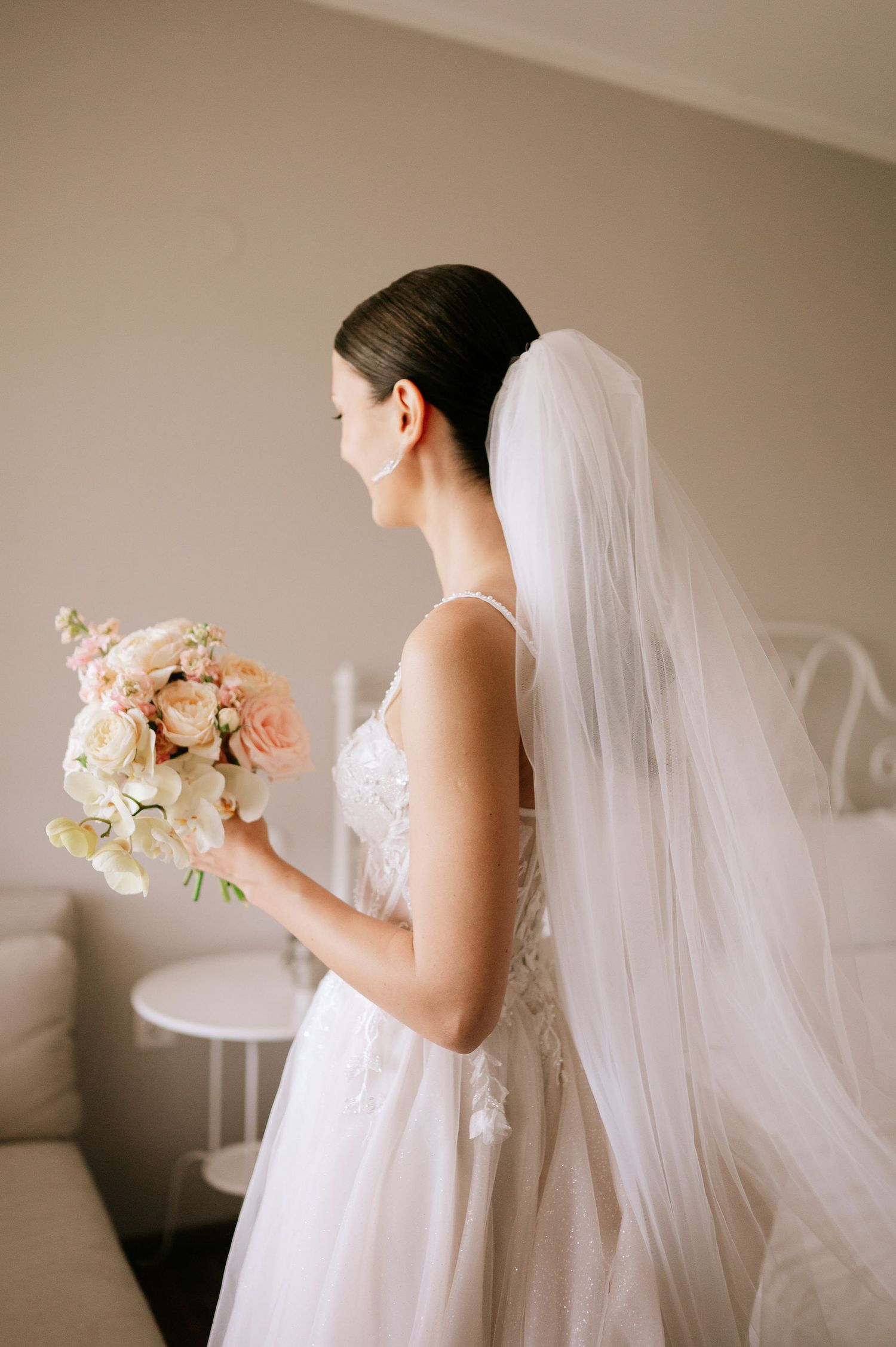 Ethereal bridal portrait with soft lighting showcasing elegant gown and floral bouquet.