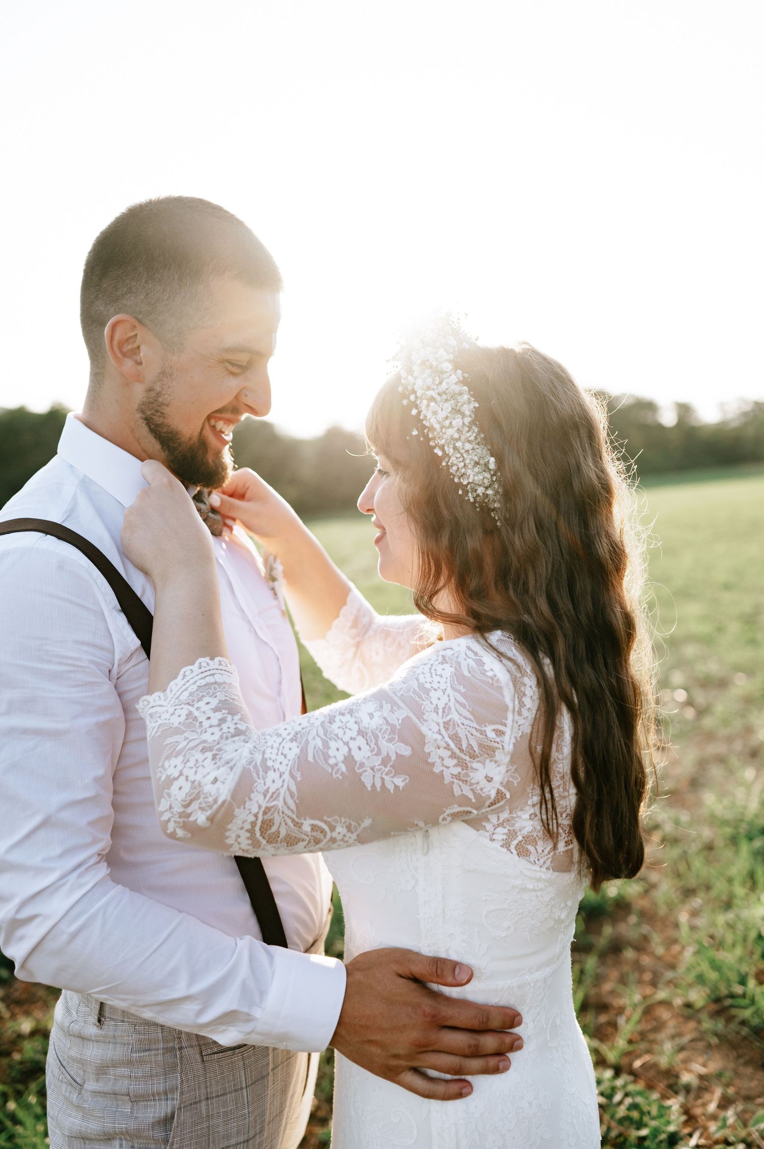 A couple in wedding attire shares joyful moments during their sunset photoshoot.