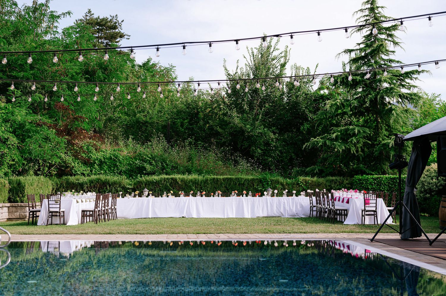 Elegant outdoor wedding reception setup with string lights and white chairs overlooking a scenic view.