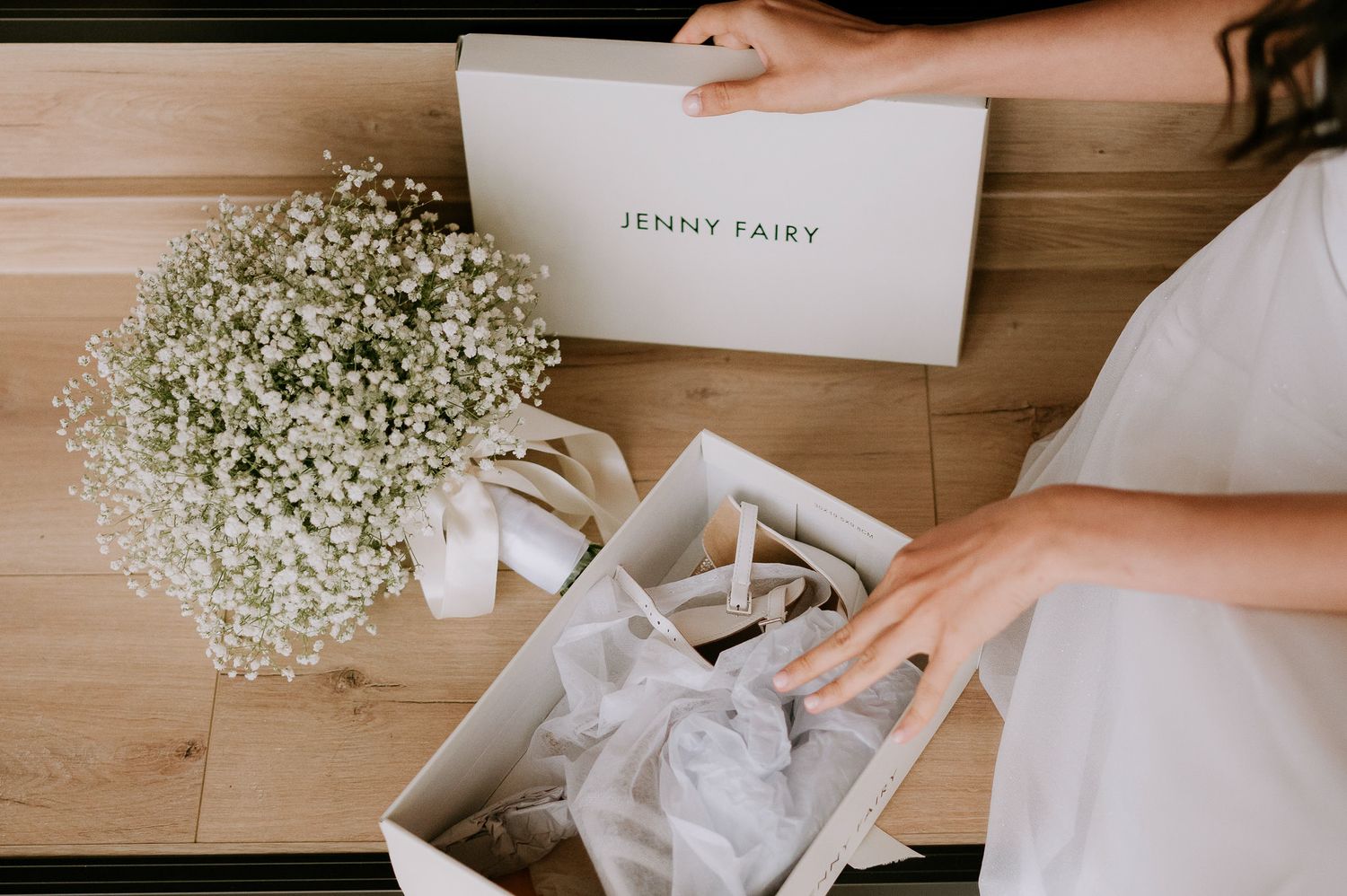 Wedding details with baby's breath bouquet and a white box on wooden surface.