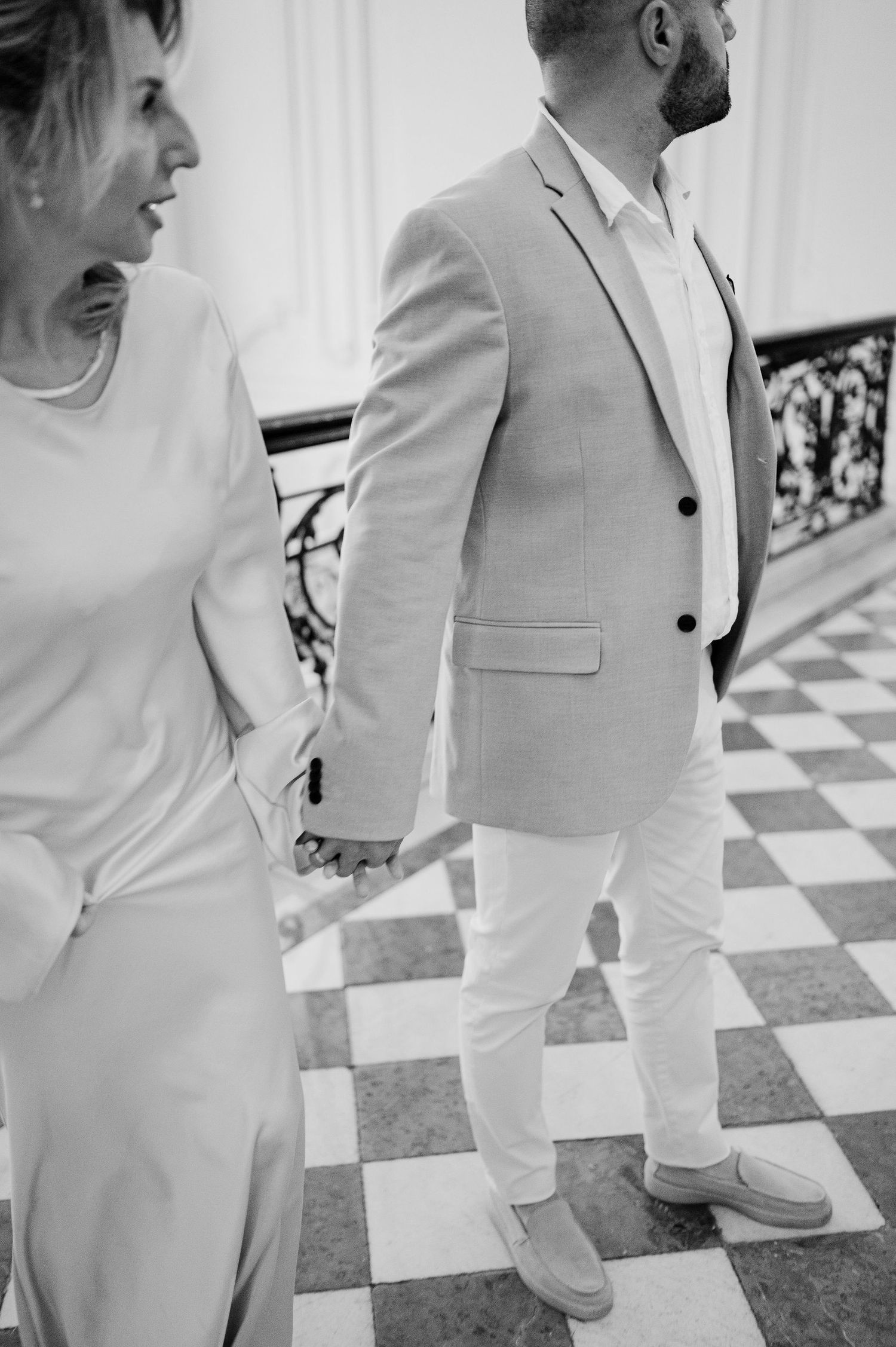 Side view of two people in white formal attire standing together.