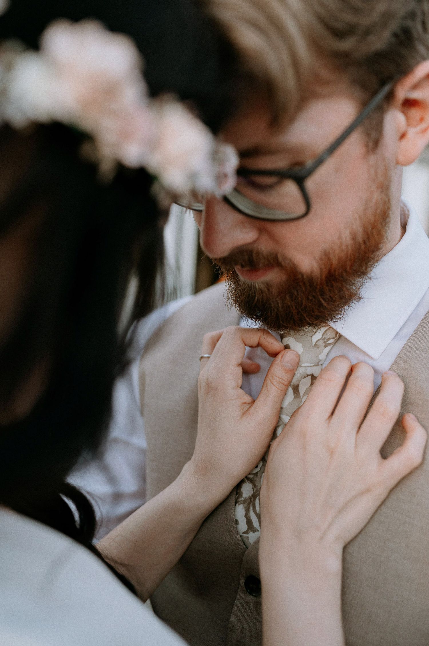 A close-up series showing hands adjusting a gray patterned tie against a white shirt.
