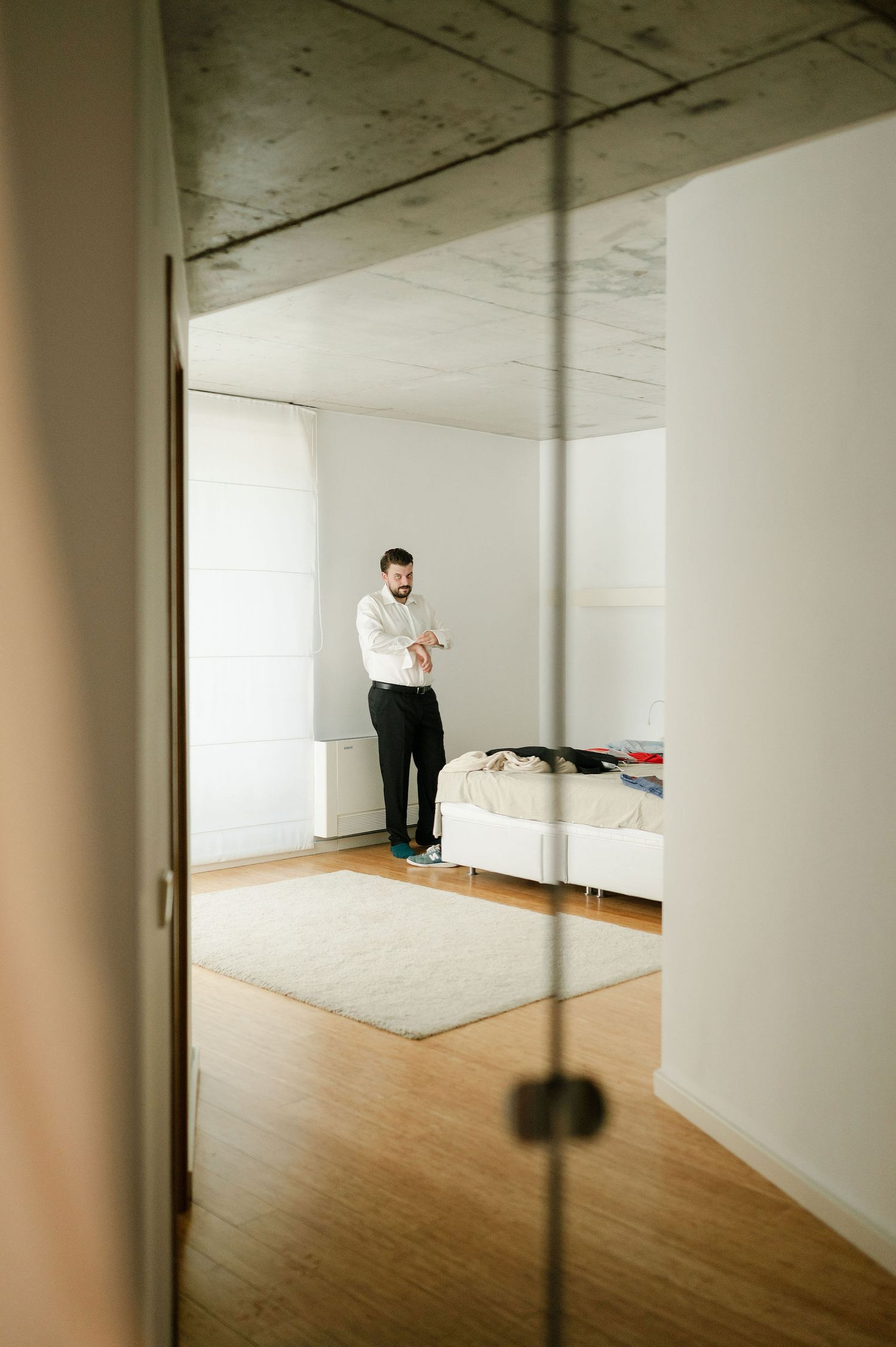 Wide view of minimalist room with people preparing on white carpet near window.